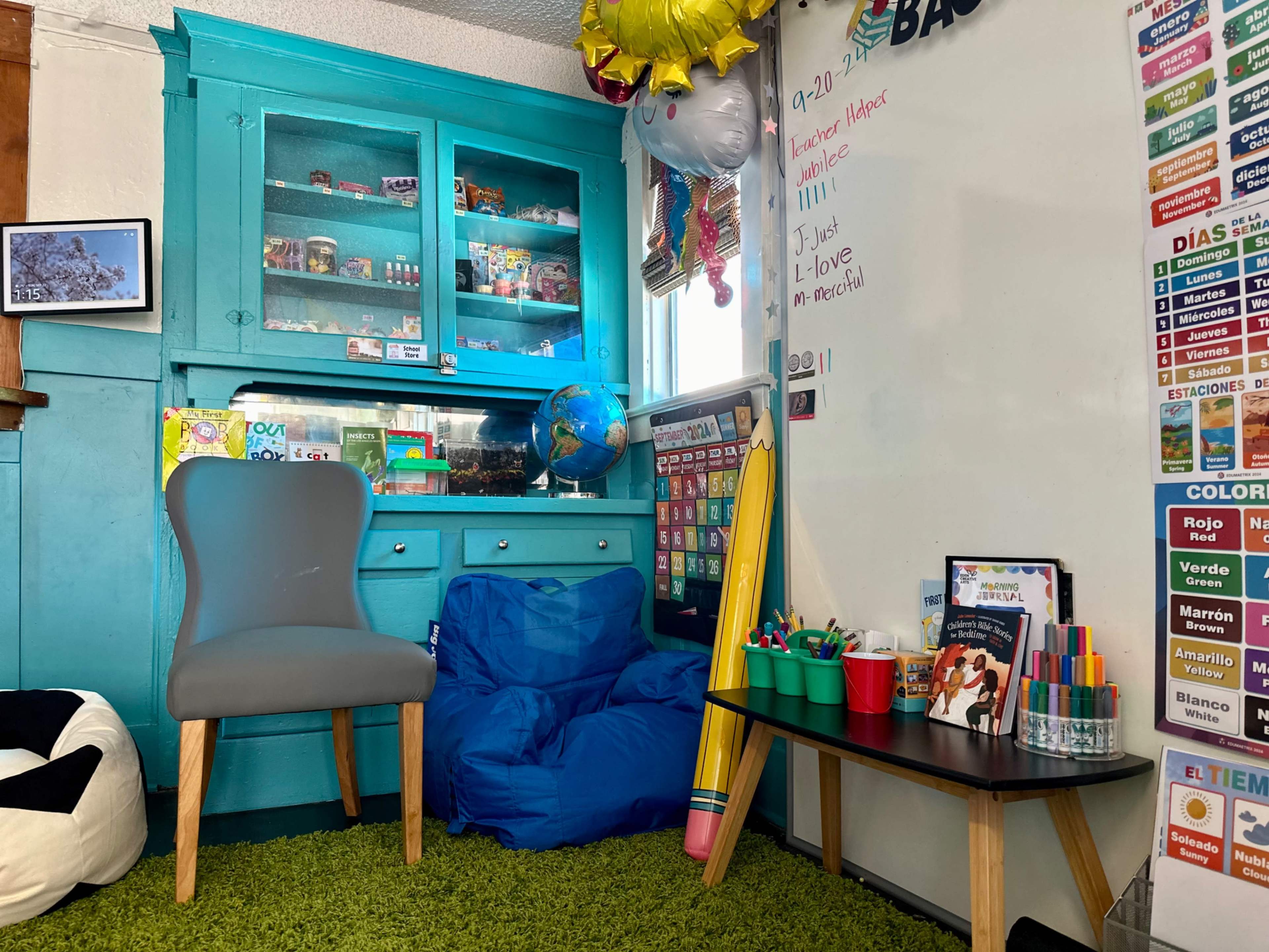 The image shows a colorful classroom or learning space featuring a turquoise cabinet, a blue beanbag chair, and various educational materials on a wall.