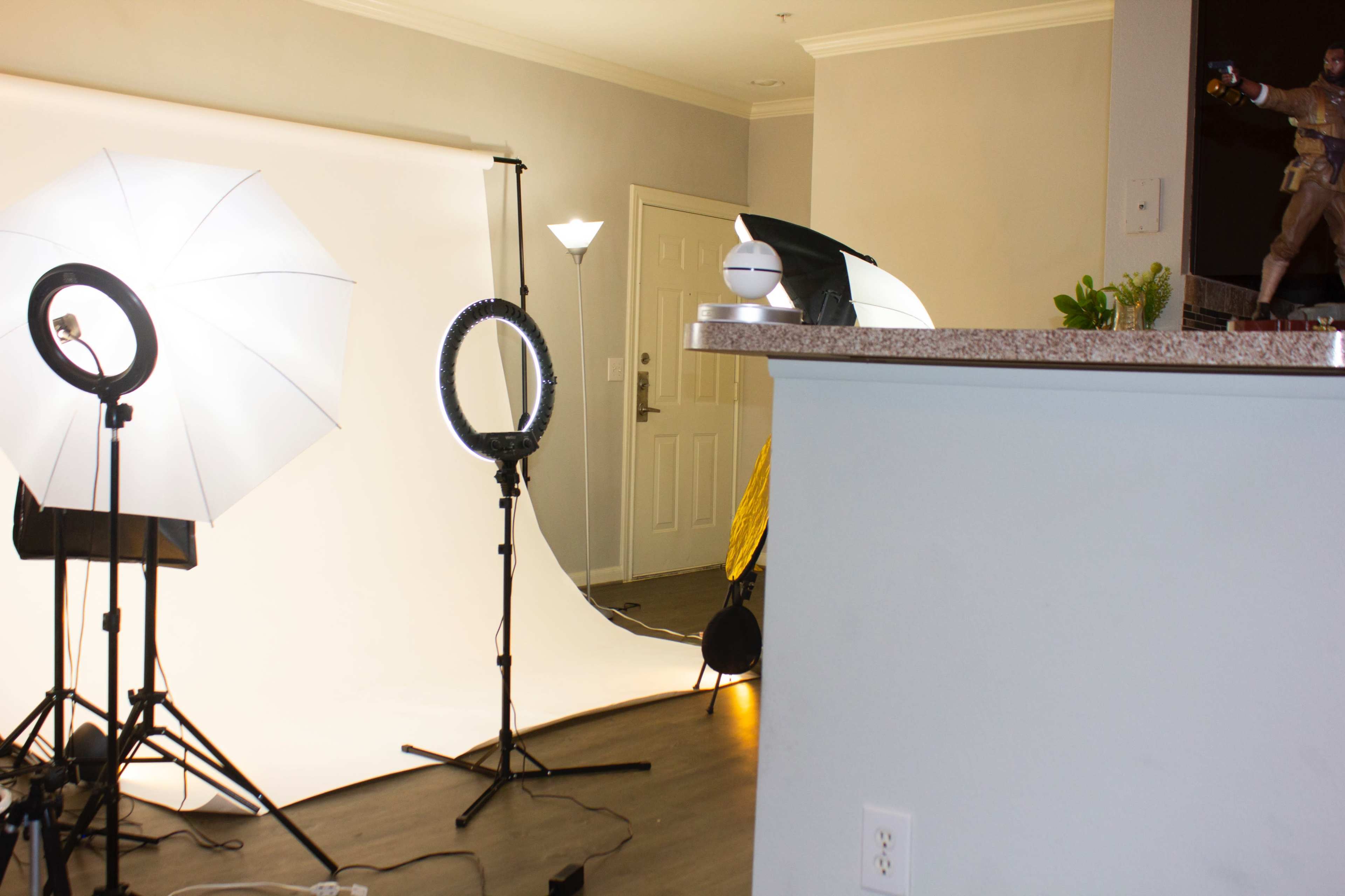 A studio setup with lighting equipment, a photography backdrop, and a decorative figure on a countertop.