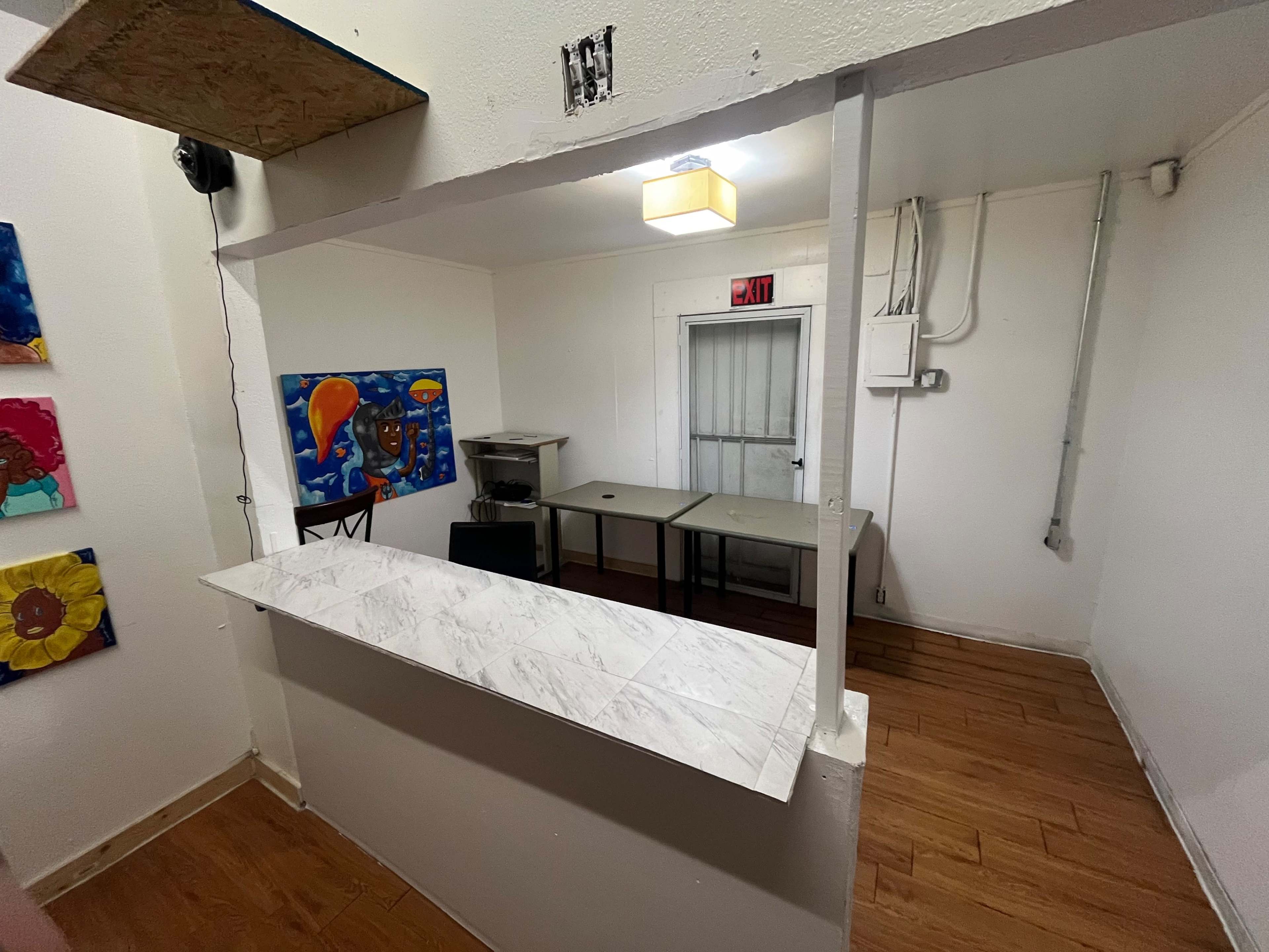 A small room with a counter, tables, and colorful artwork on the walls.