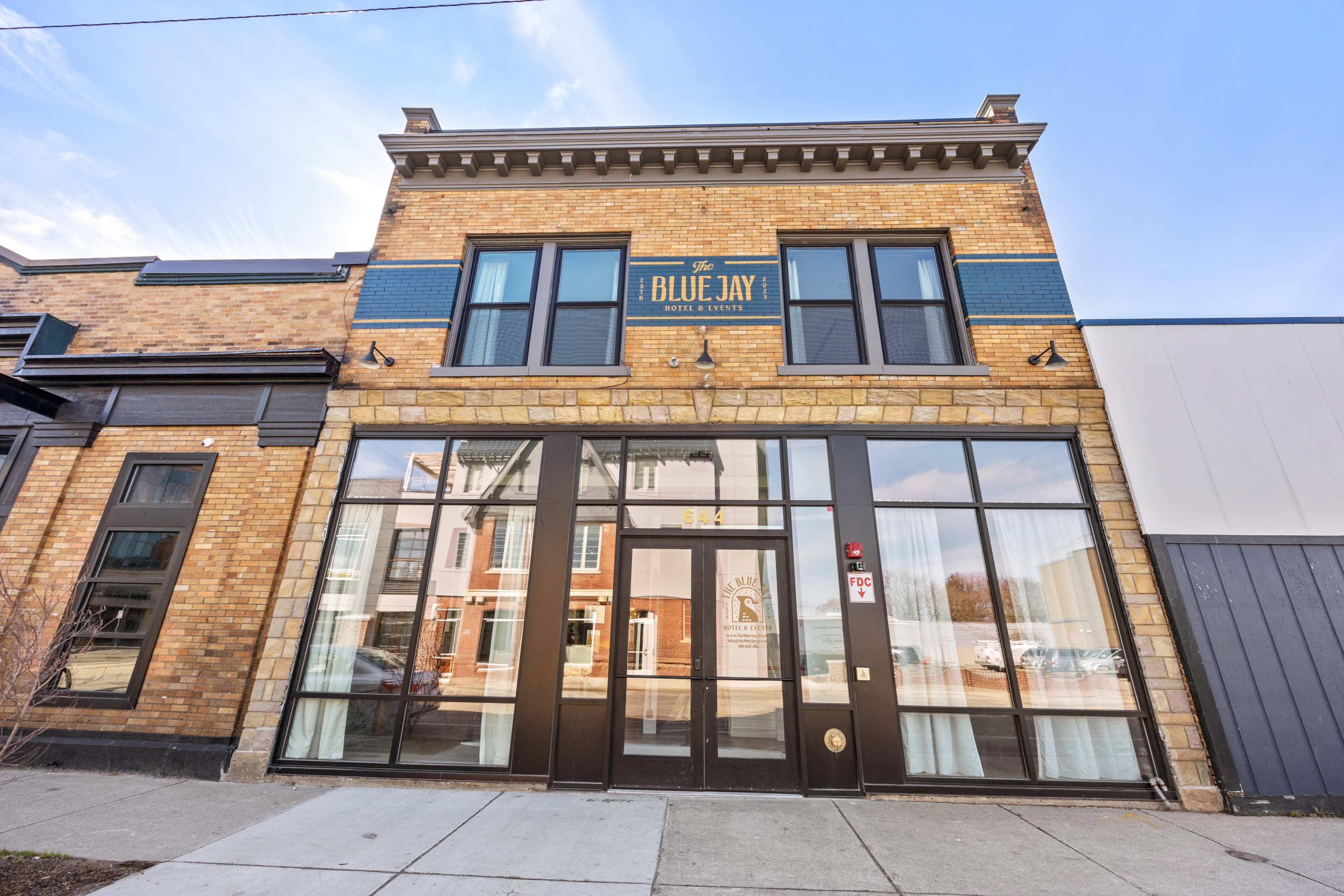 A two-story brick building with large glass windows and a sign reading "The Blue Jay" on the facade.
