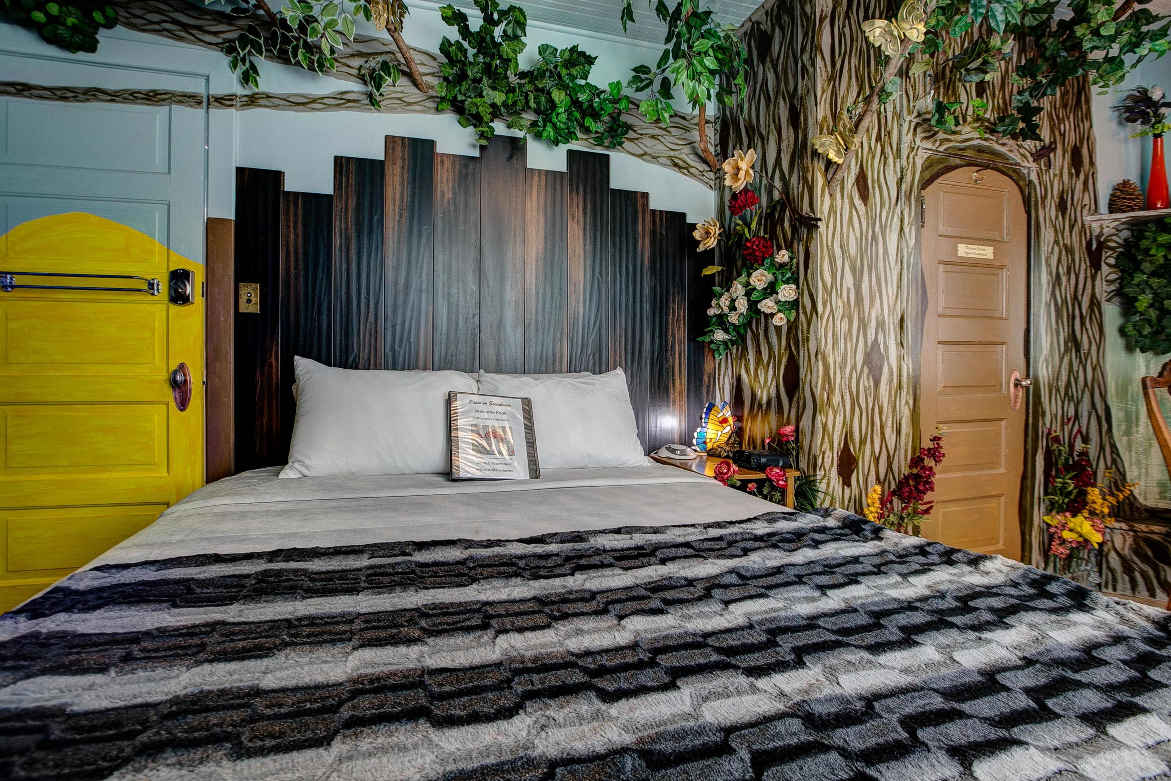 A creatively decorated bedroom featuring a wooden headboard, a tree-themed mural on the walls, and a bright yellow door.