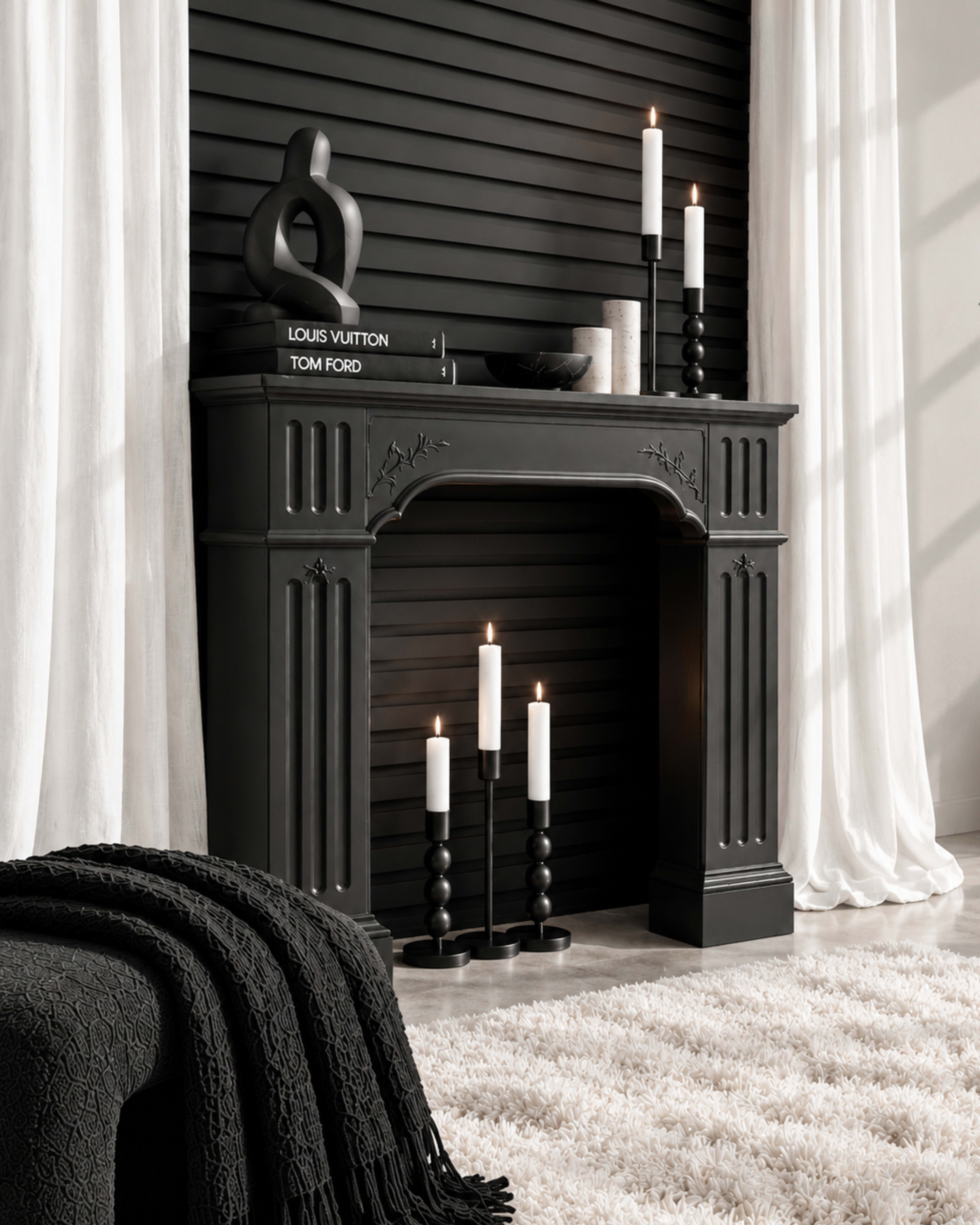 A black fireplace with decorative details is positioned against a dark, slatted wall, surrounded by candles and a cozy throw.