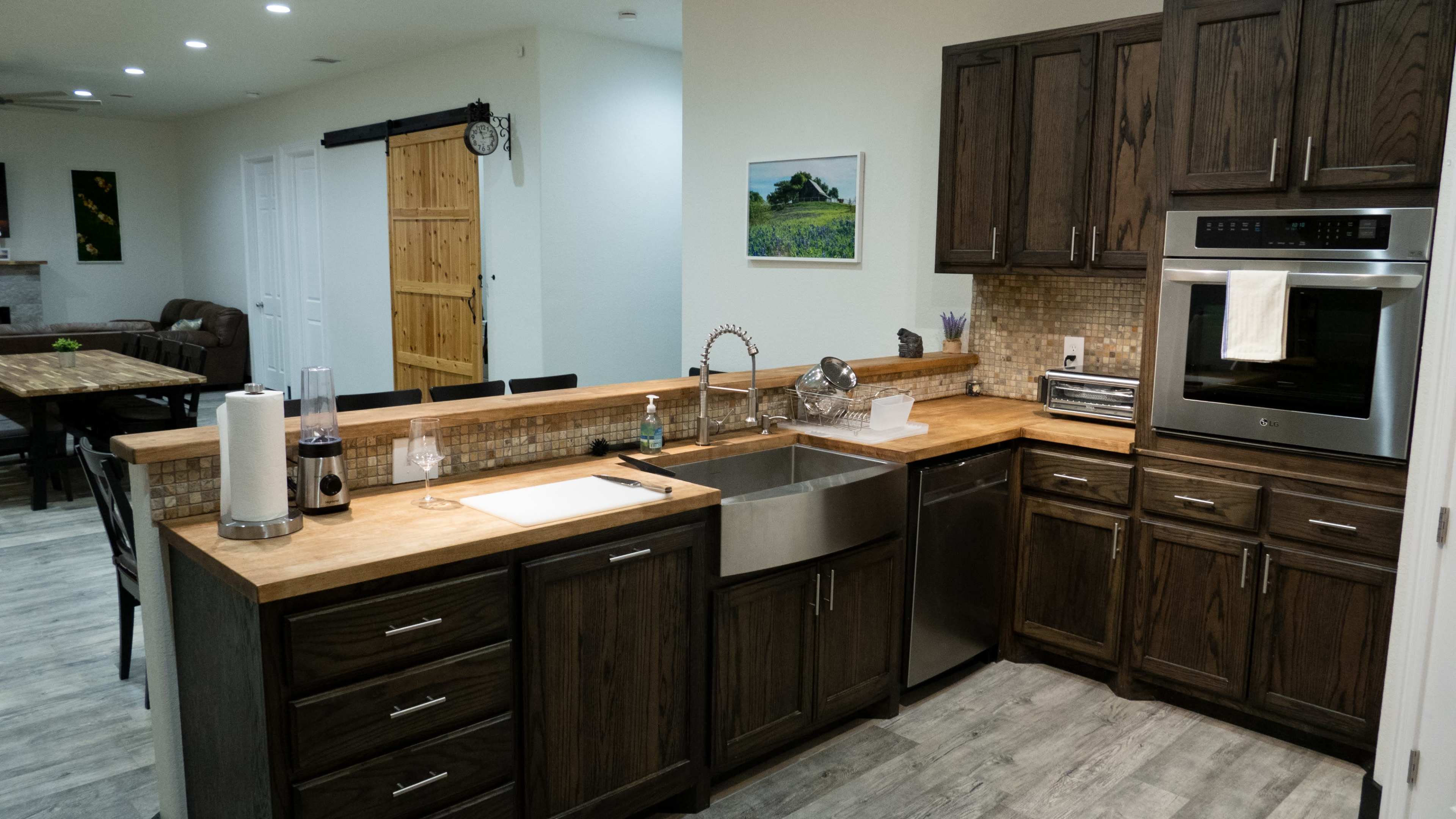 A modern kitchen with dark wooden cabinets, a stainless steel sink, and a countertop made of light-colored wood.