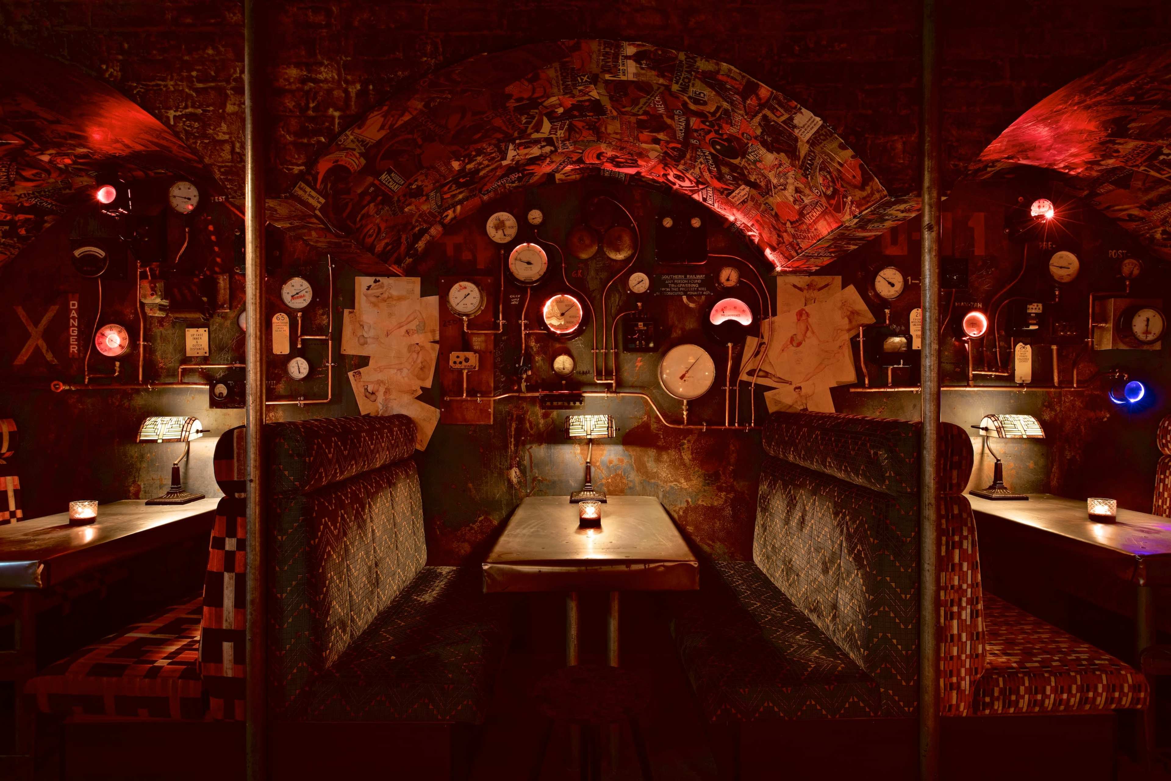 A dimly lit, atmospheric restaurant interior featuring booths with patterned upholstery and various clocks mounted on the walls.