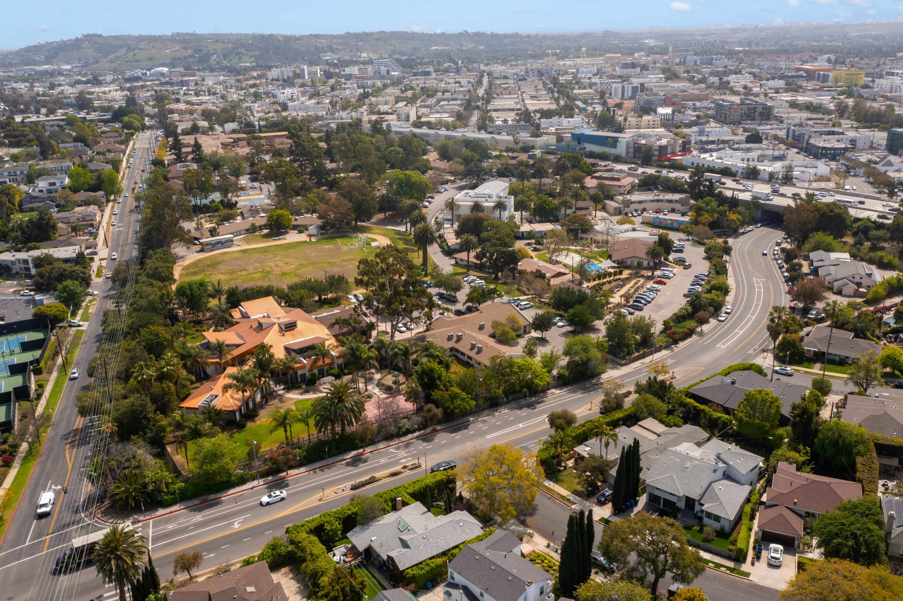 Aerial view of a suburban area featuring a park, residential homes, and winding roads.