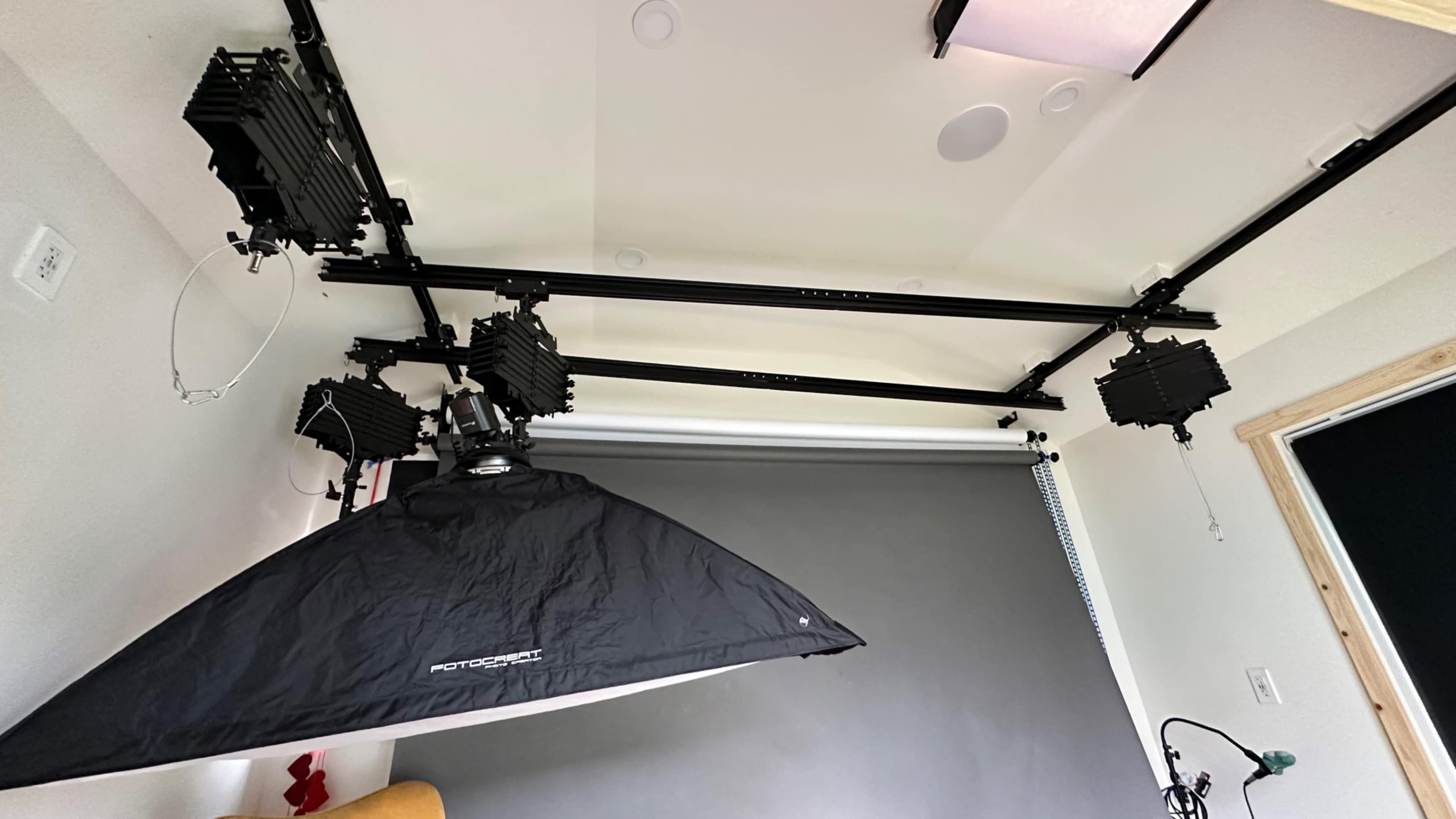 A photography setup with overhead lighting fixtures and a backdrop in a studio.