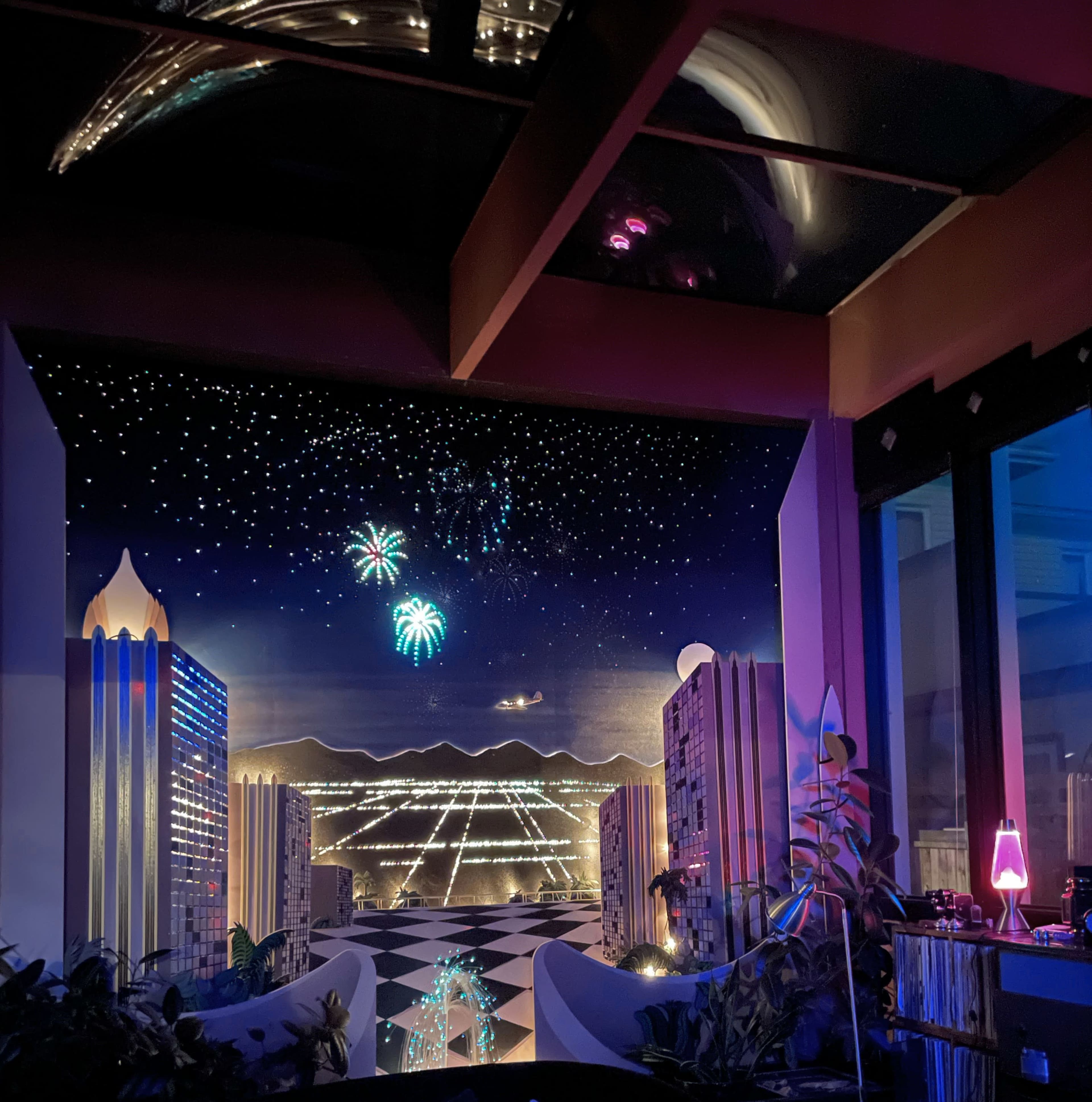 A colorful mural depicting a night cityscape with fireworks in the sky and stylized buildings on either side.