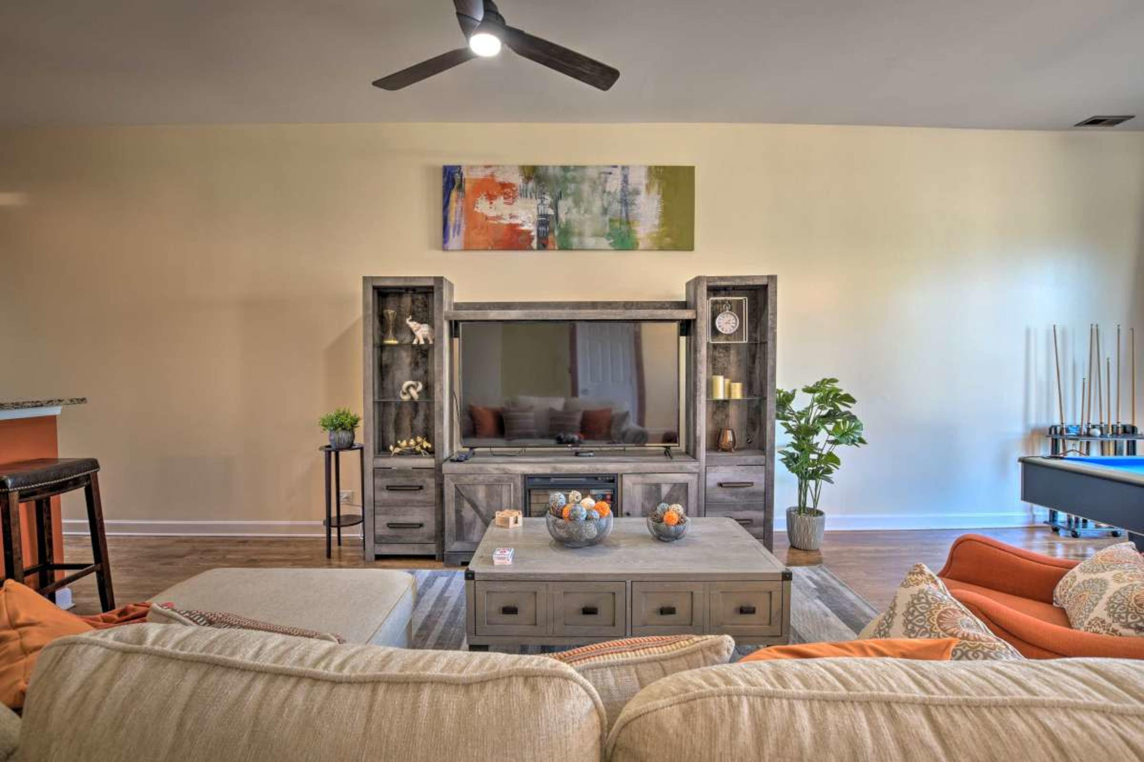 The scene features a living room with a television center, a coffee table with decorative items, and a sofa set arranged around it.