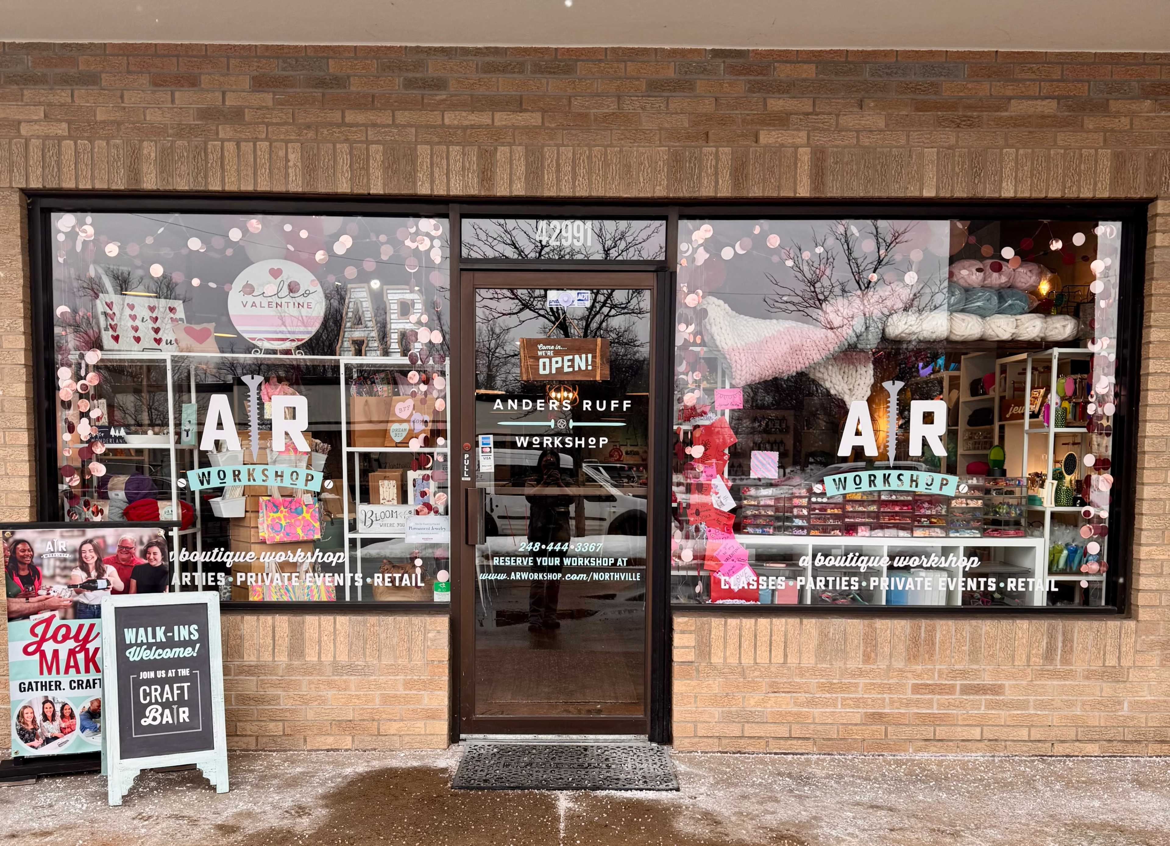 The storefront features a glass window adorned with colorful decorations and signage for "Anders Ruff Workshop," indicating it offers craft workshops and retail.