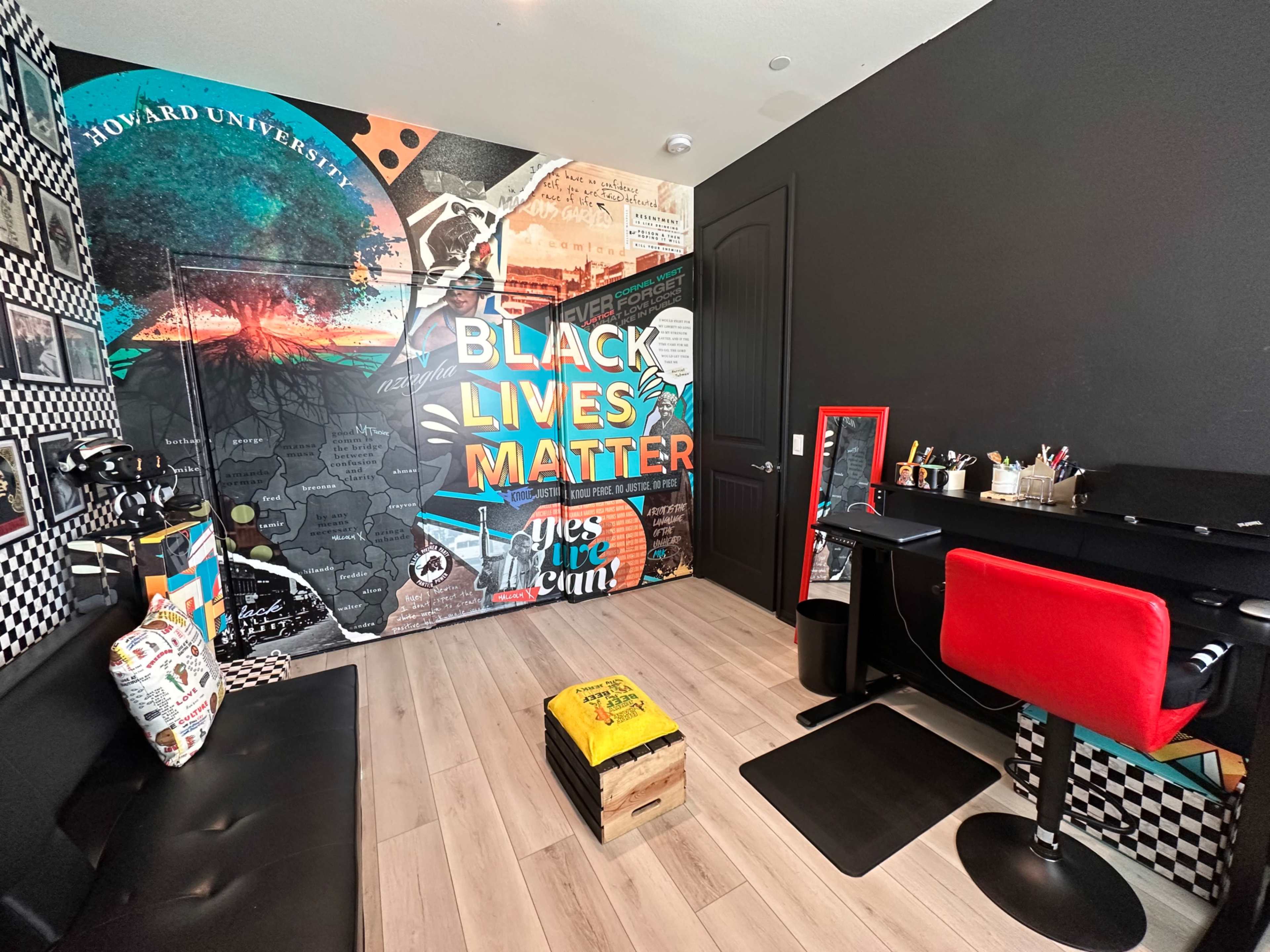 The room features a mural with the phrase "Black Lives Matter" on one wall, a desk with red seating, and a variety of decorative items and artwork.