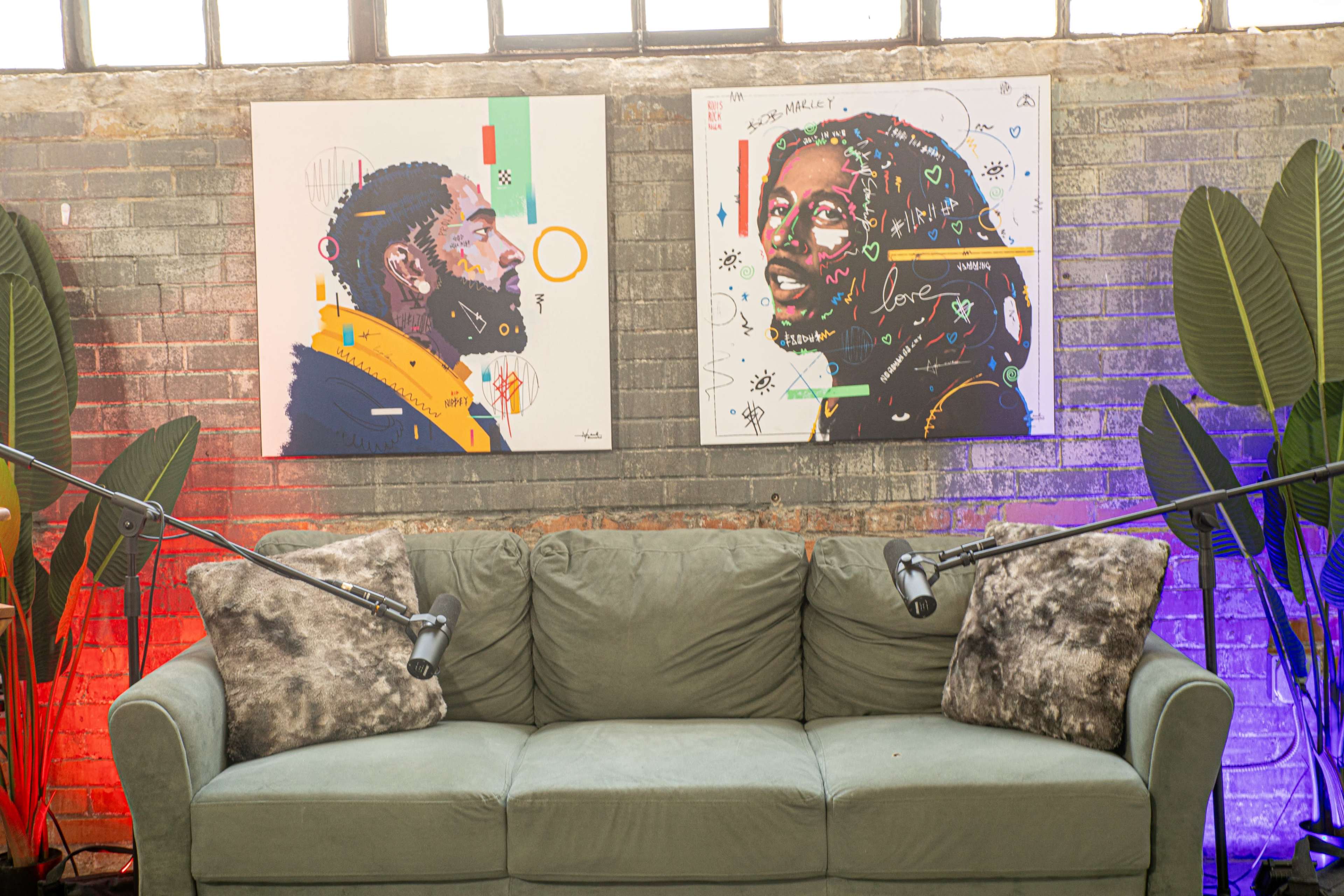A green couch placed between two colorful portraits on the wall, with studio lights illuminating the space.