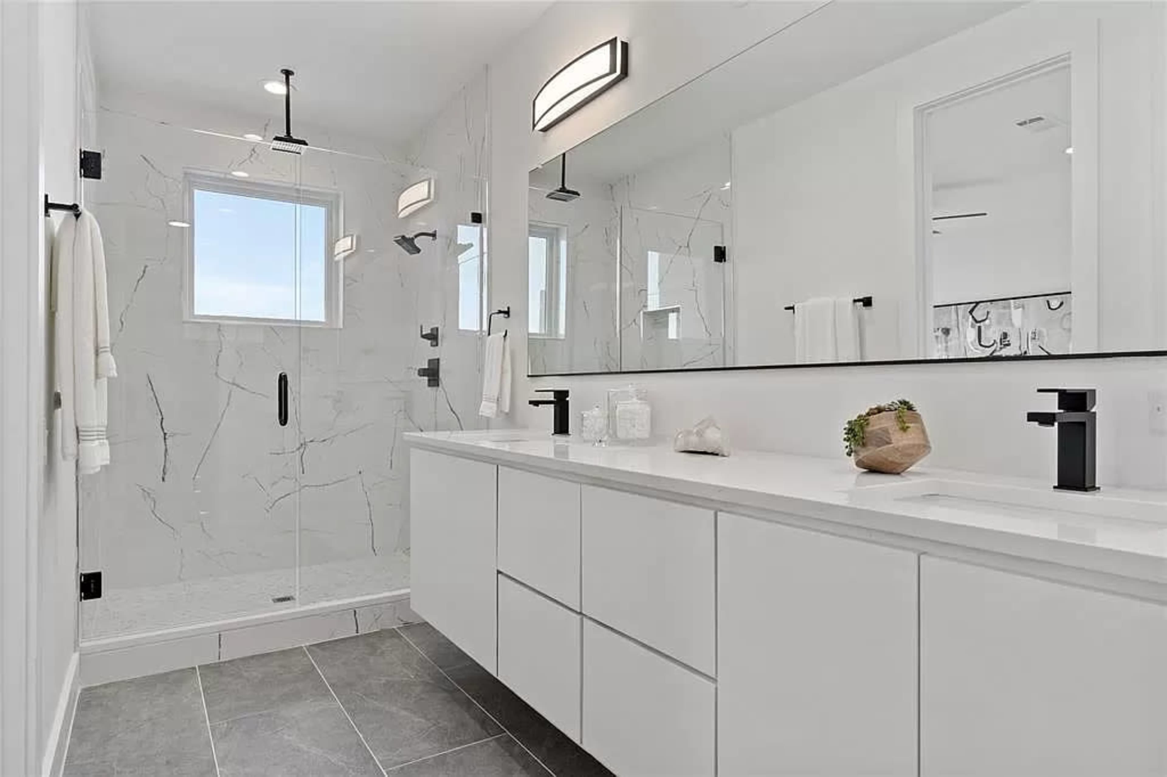 A modern bathroom featuring a walk-in shower with a glass enclosure and a double sink vanity with a sleek design.