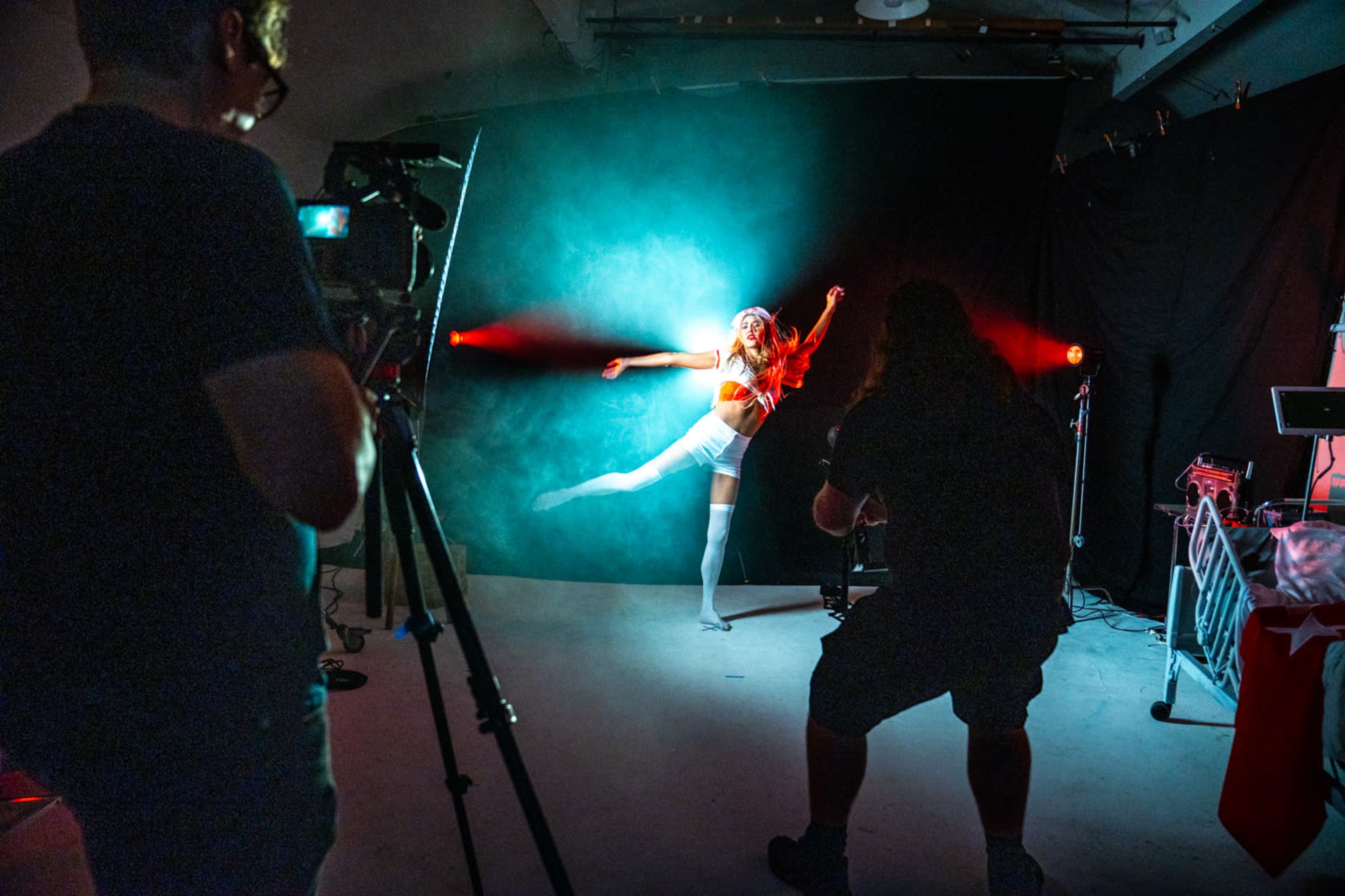 A dancer performs against a foggy backdrop while two photographers capture the scene with cameras.