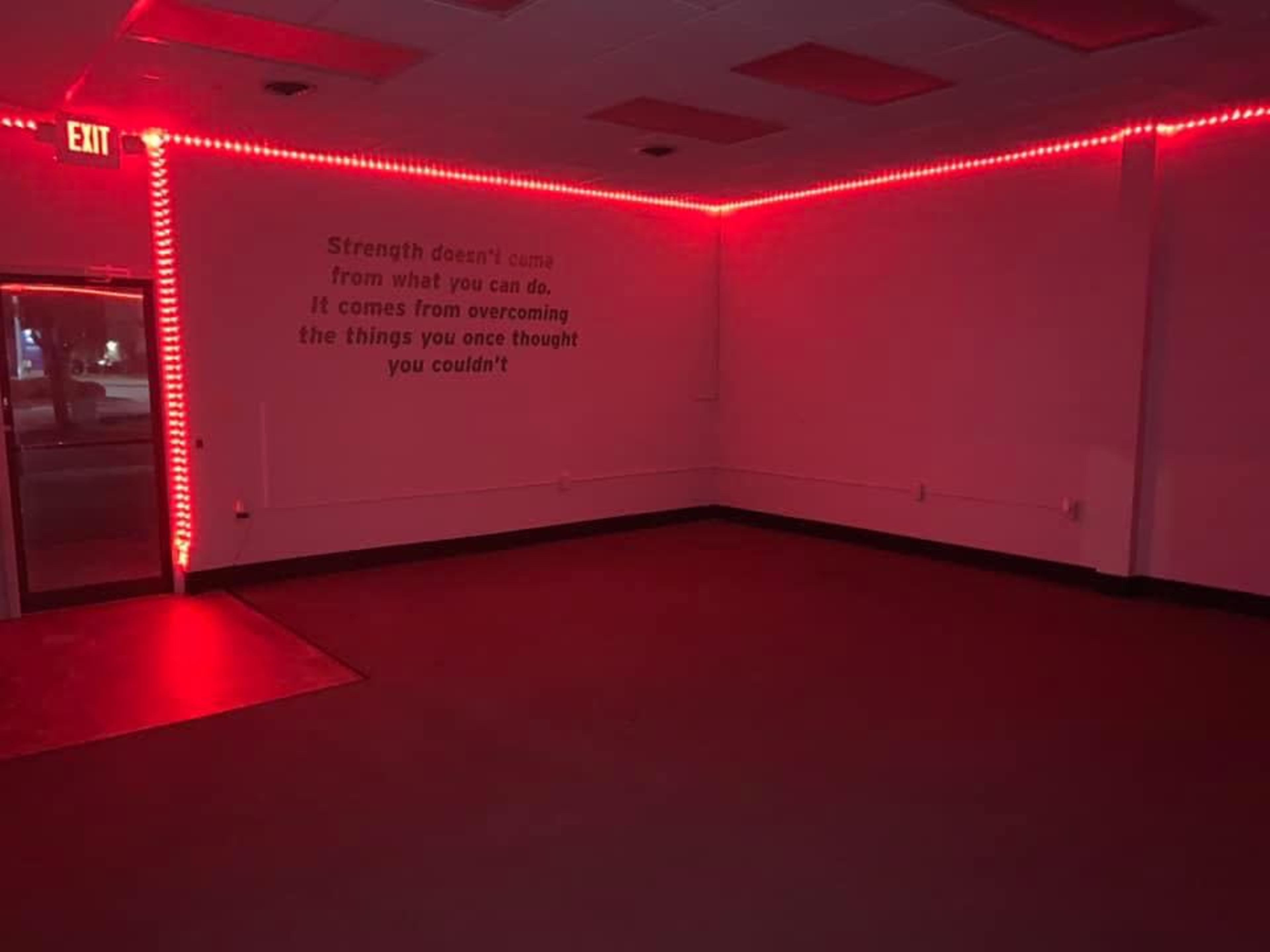 An empty room lit with red LED lights, featuring a motivational quote on the wall.