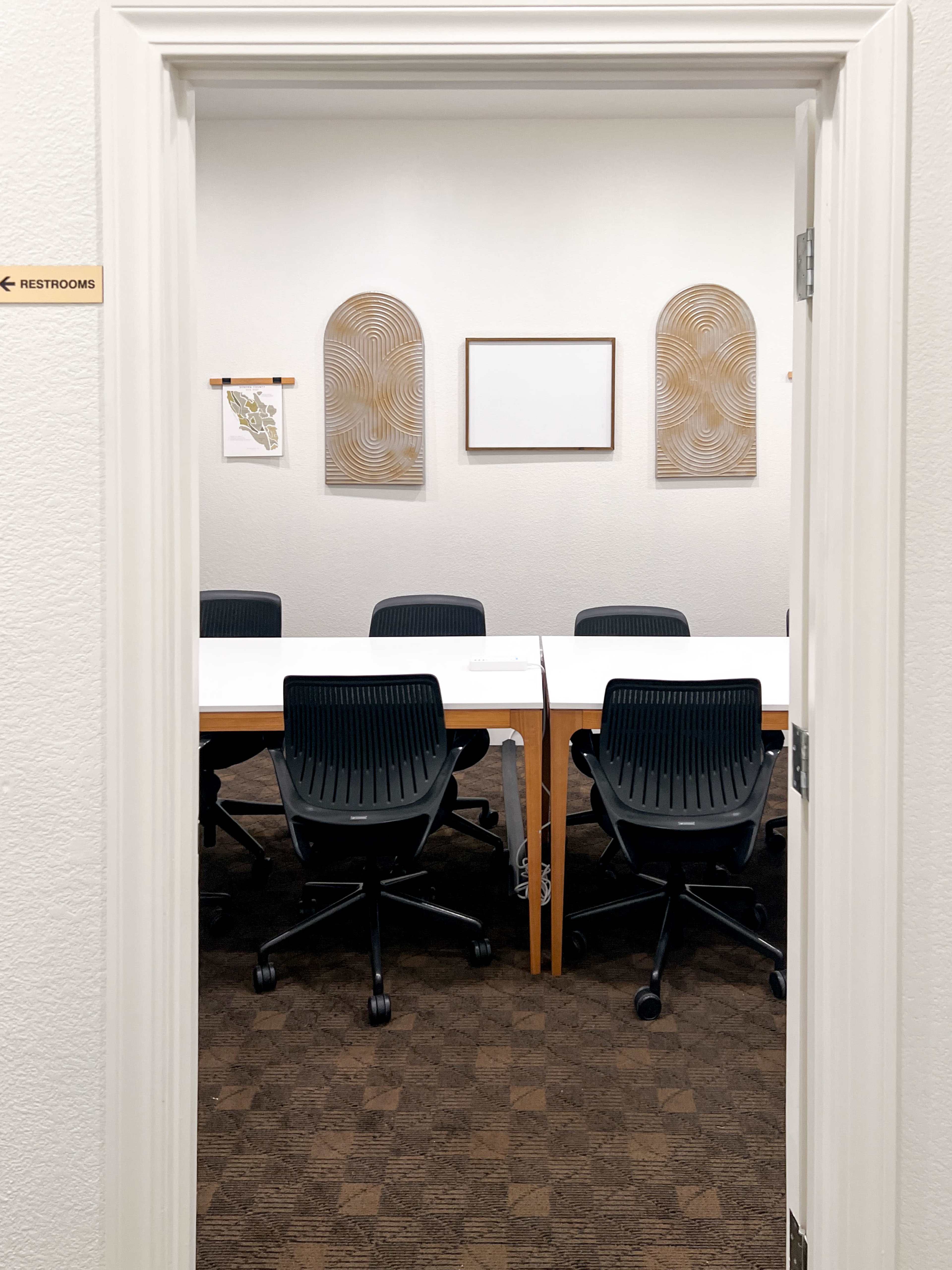 A conference room with a long table and several rolling chairs is visible through an open doorway.