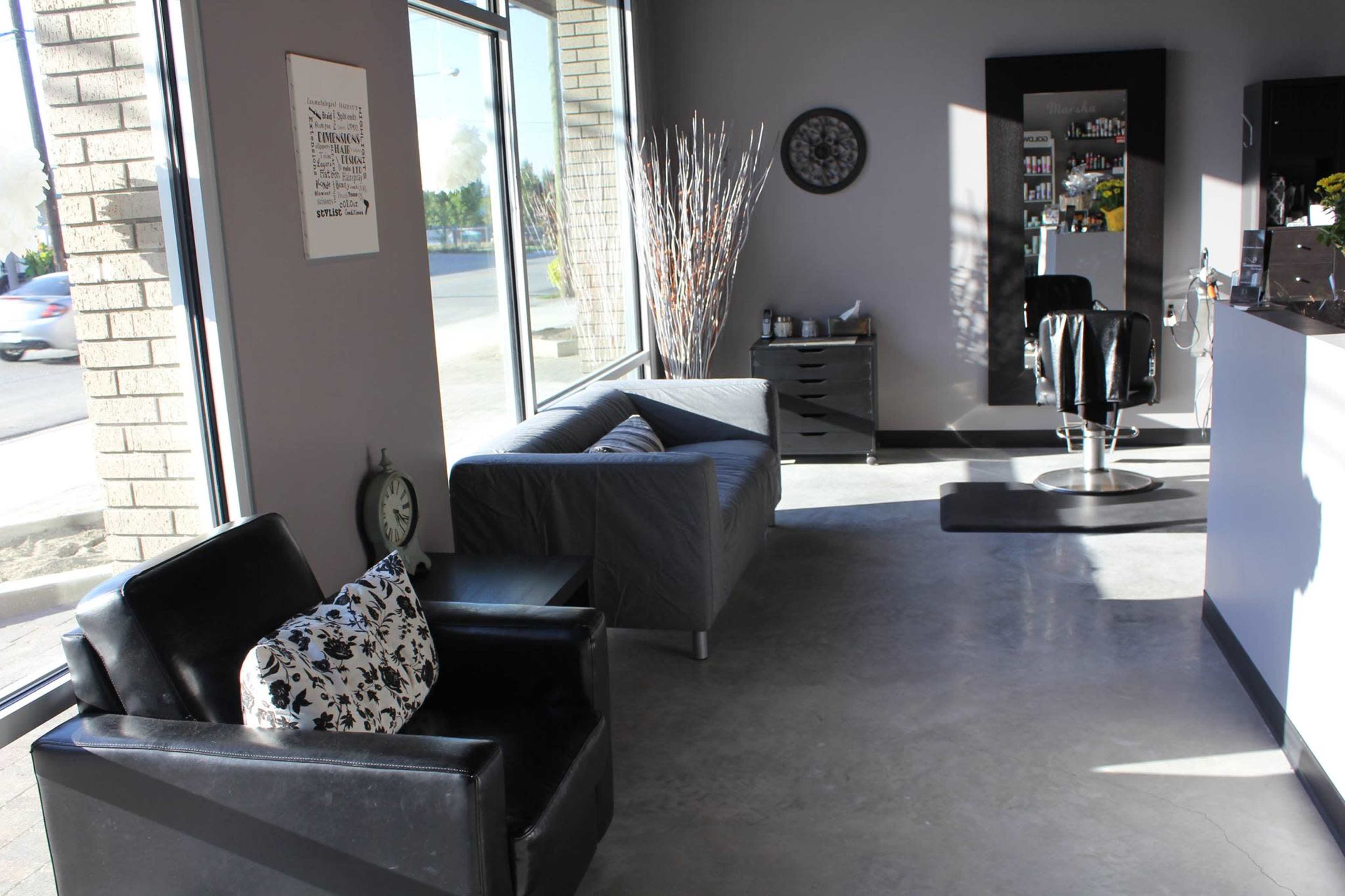 The image shows a modern salon interior with two seating areas, a hair styling station, and large windows letting in natural light.
