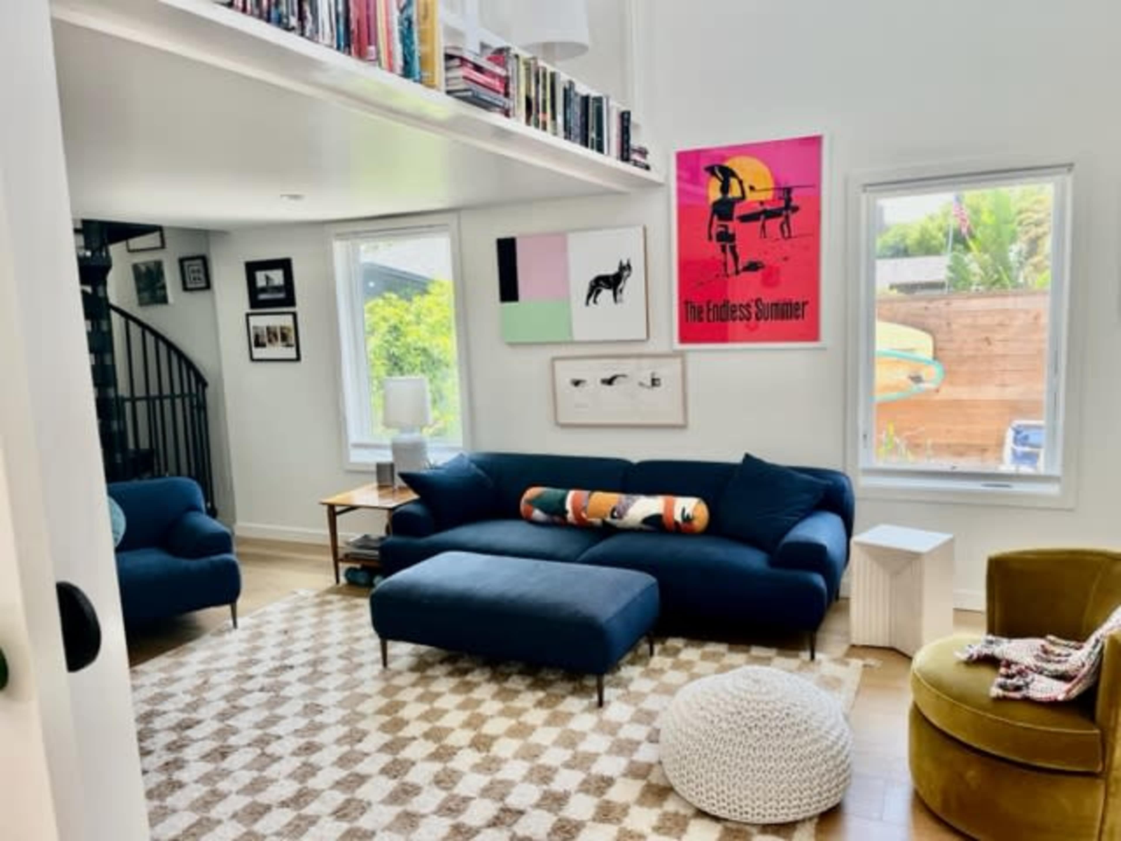 A modern living room with a blue couch, a patterned rug, and bright artwork on the walls.
