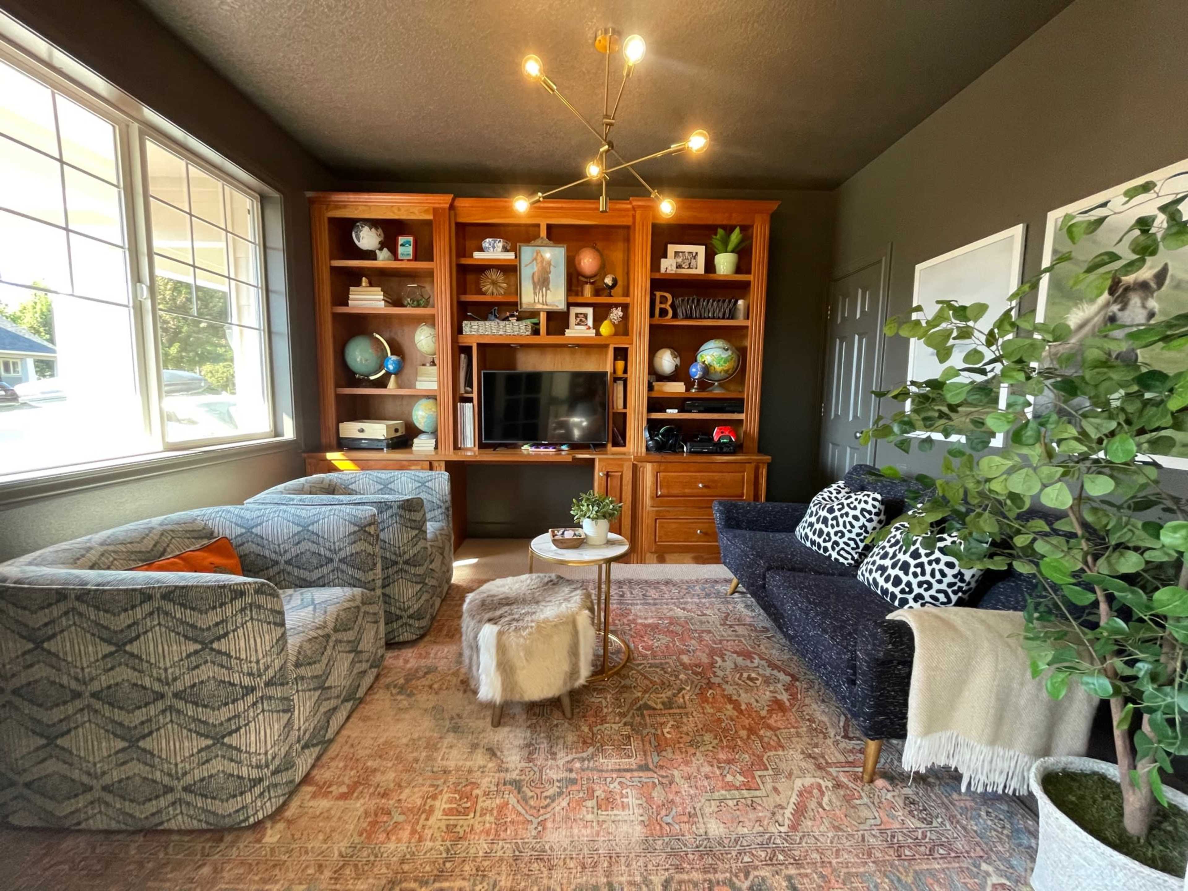 A living room with two patterned sofas, a coffee table, and a TV on a wooden shelf surrounded by decorative items.