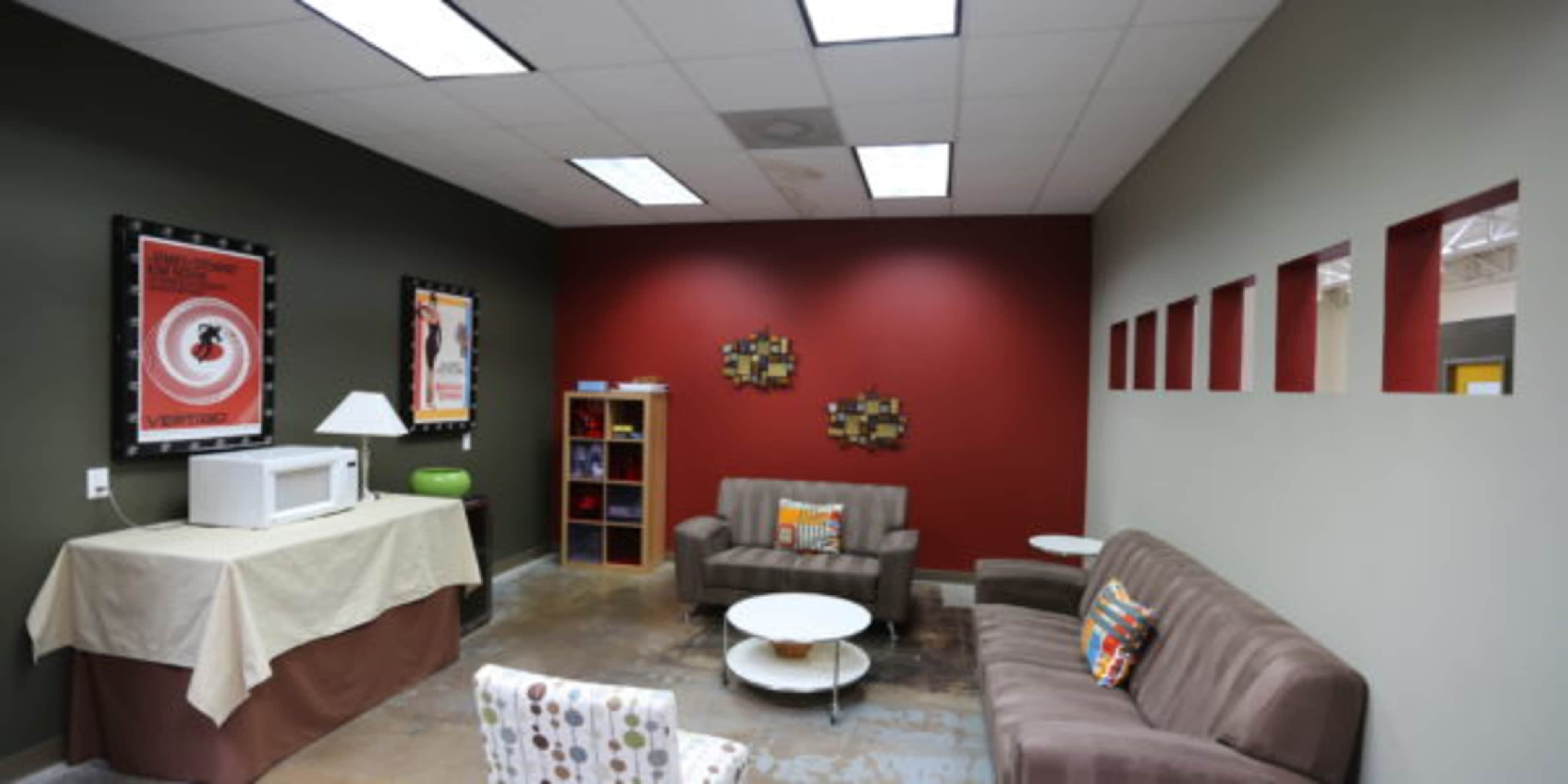 A modern lounge area featuring two upholstered sofas, a round coffee table, and a wall with square cutouts, adorned with framed artwork.
