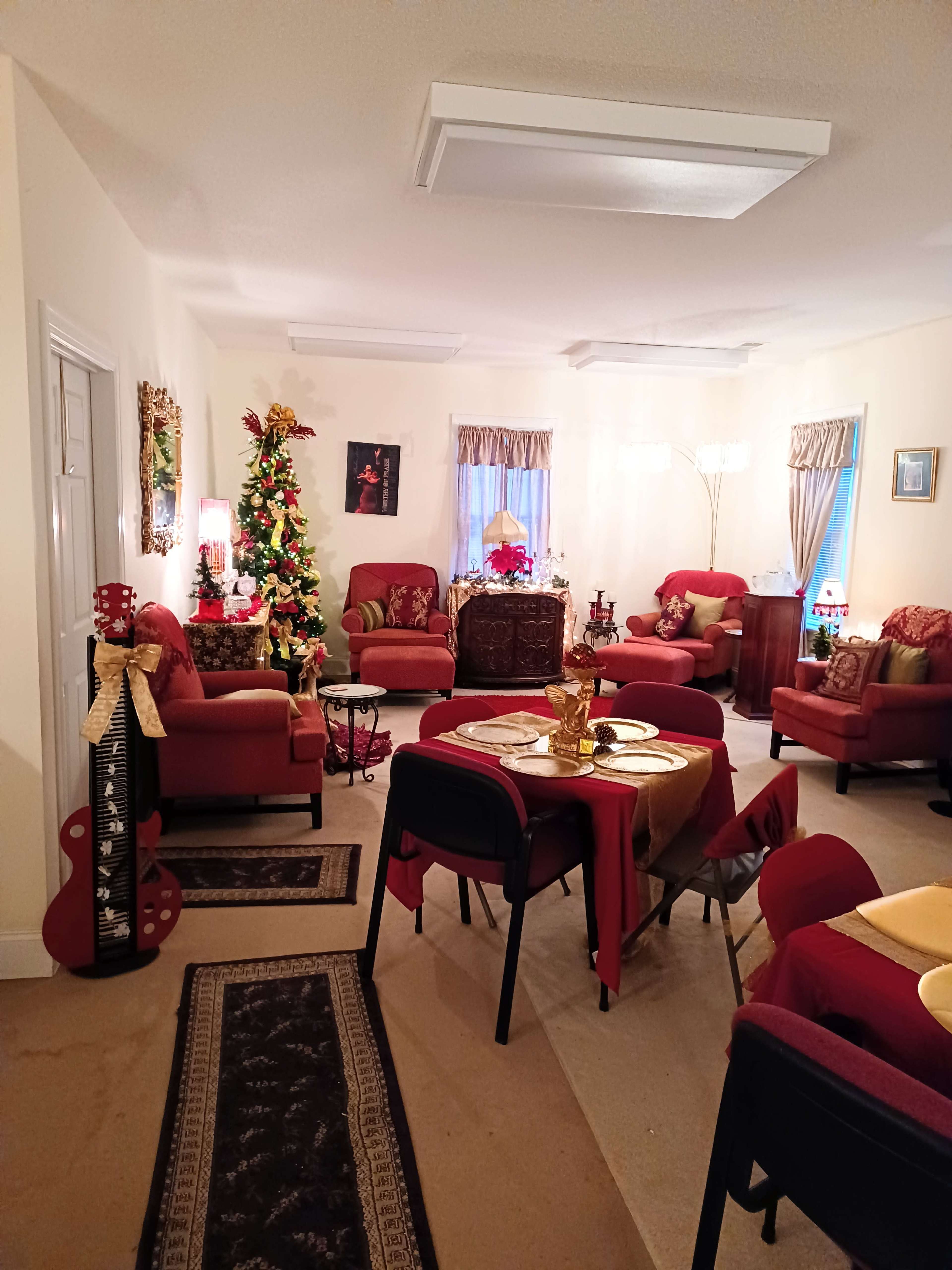 A decorated living room with red furniture, a Christmas tree, and a dining table set for a meal.