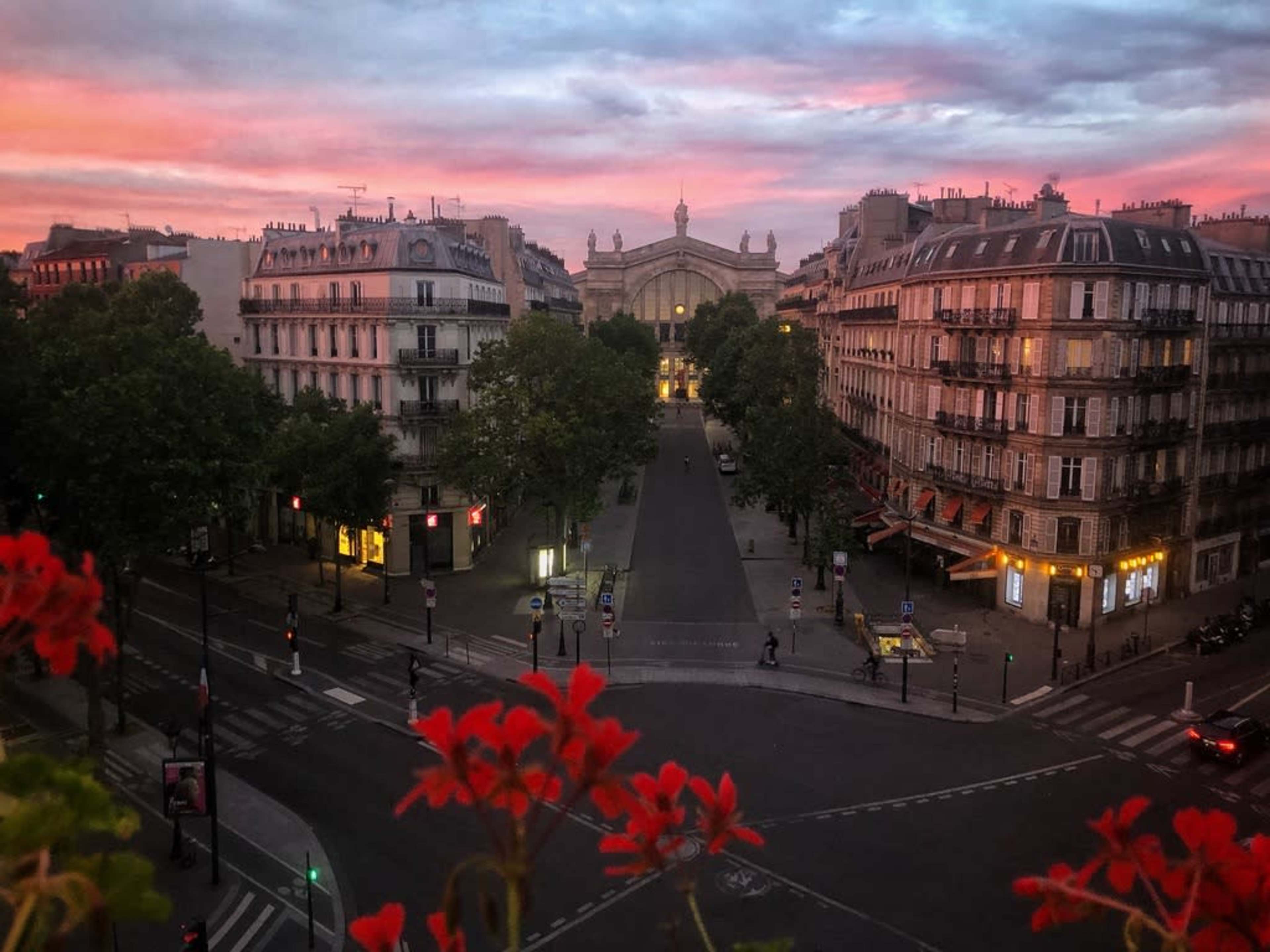 The scene shows a street in Paris at sunset, framed by buildings and trees, with a view of a grand arch in the distance.