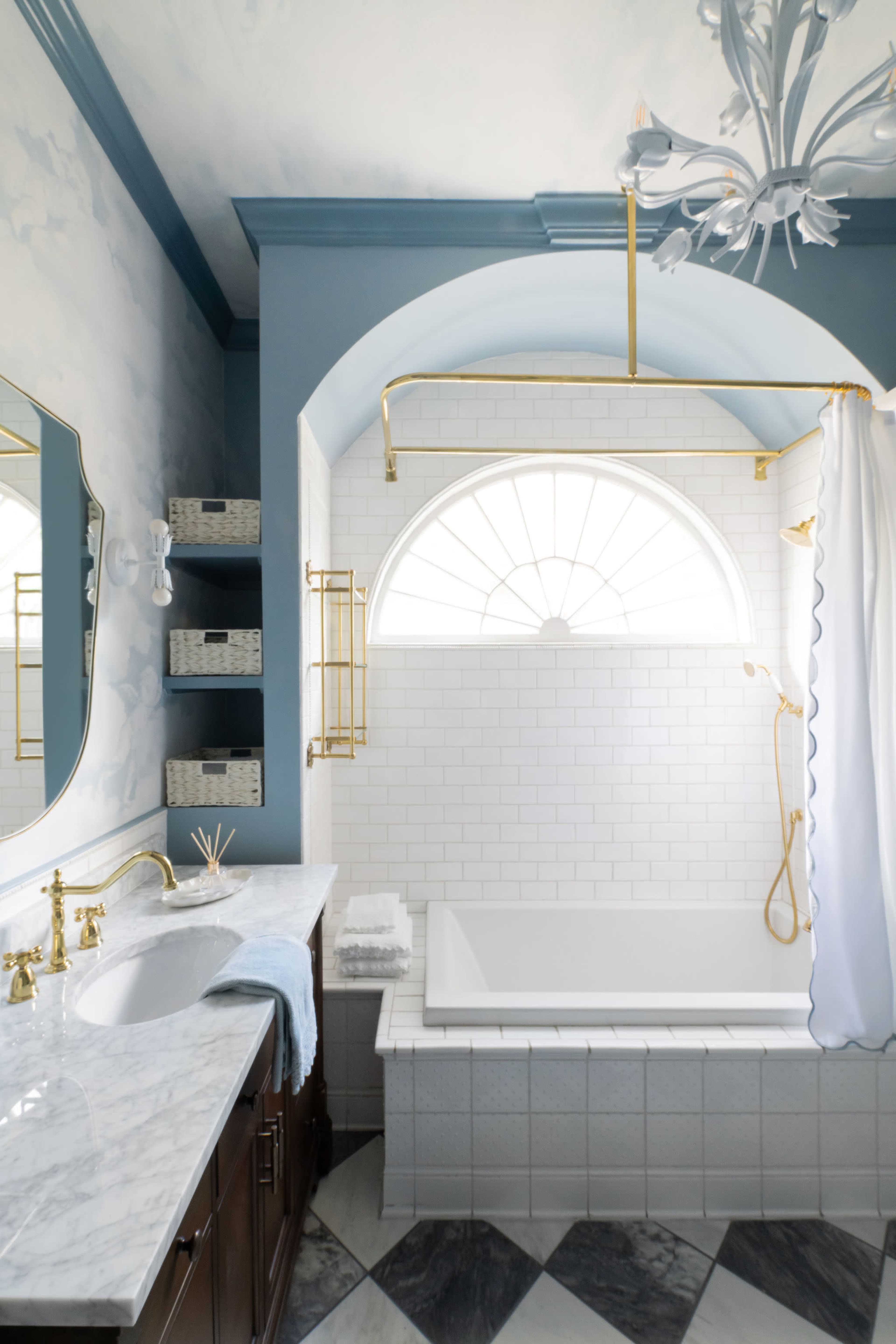 The bathroom features a marble vanity, a tub with a gold shower fixture, and a large arched window allowing natural light.