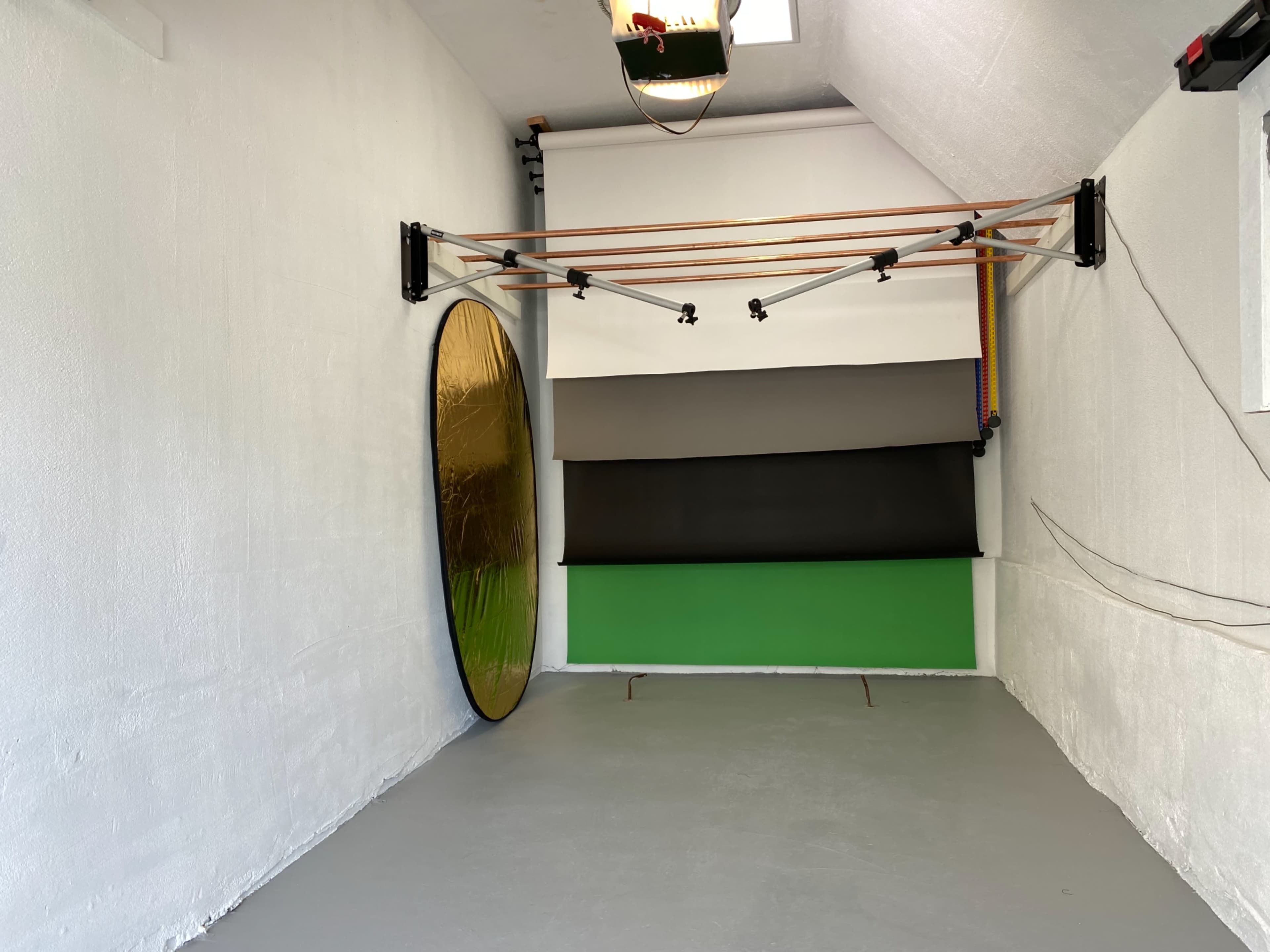 A photo studio setup featuring a backdrop system with various colored panels and a large reflective disc mounted on the wall.