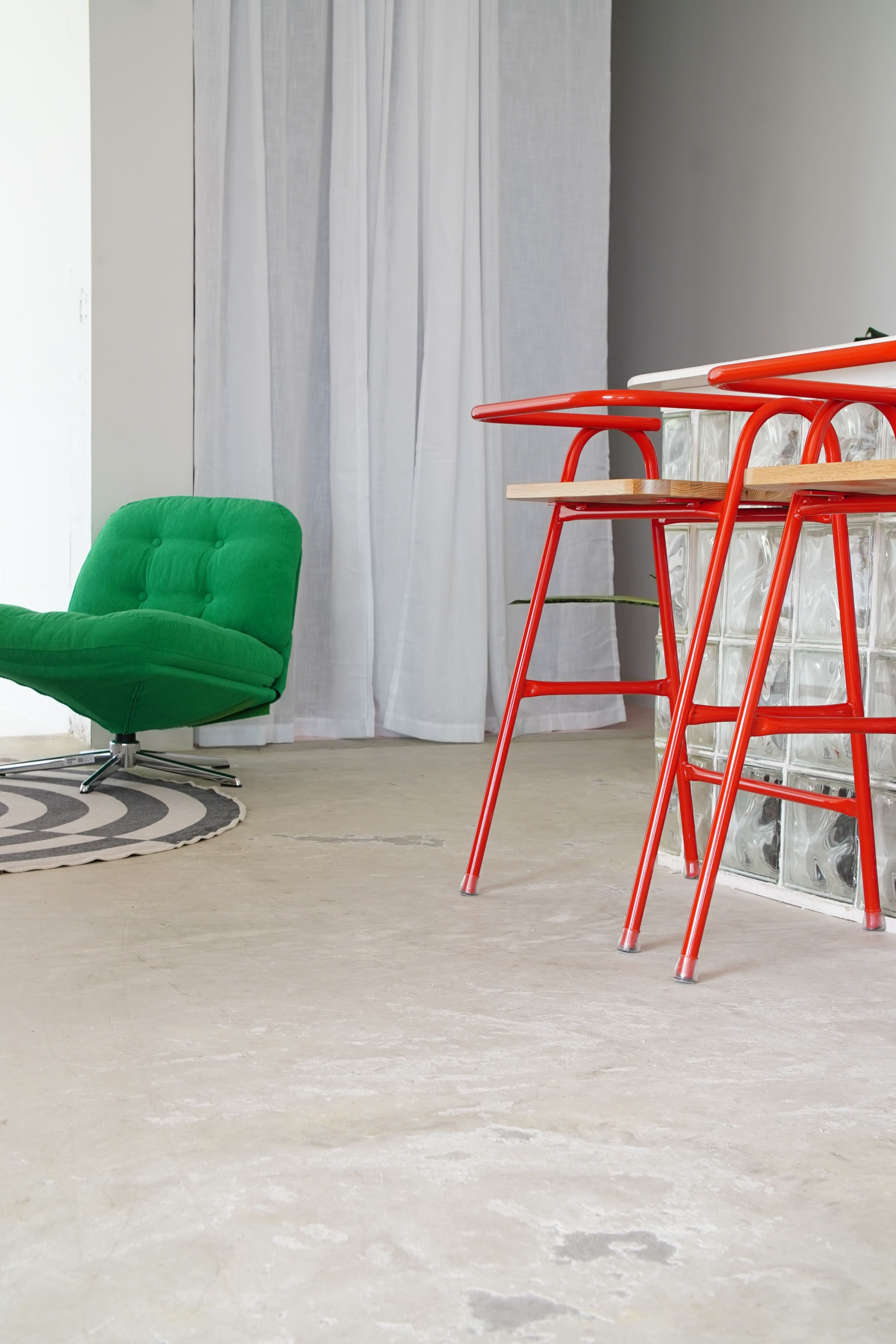 The scene features a green chair, a circular rug, and red barstools positioned near a glass block wall.