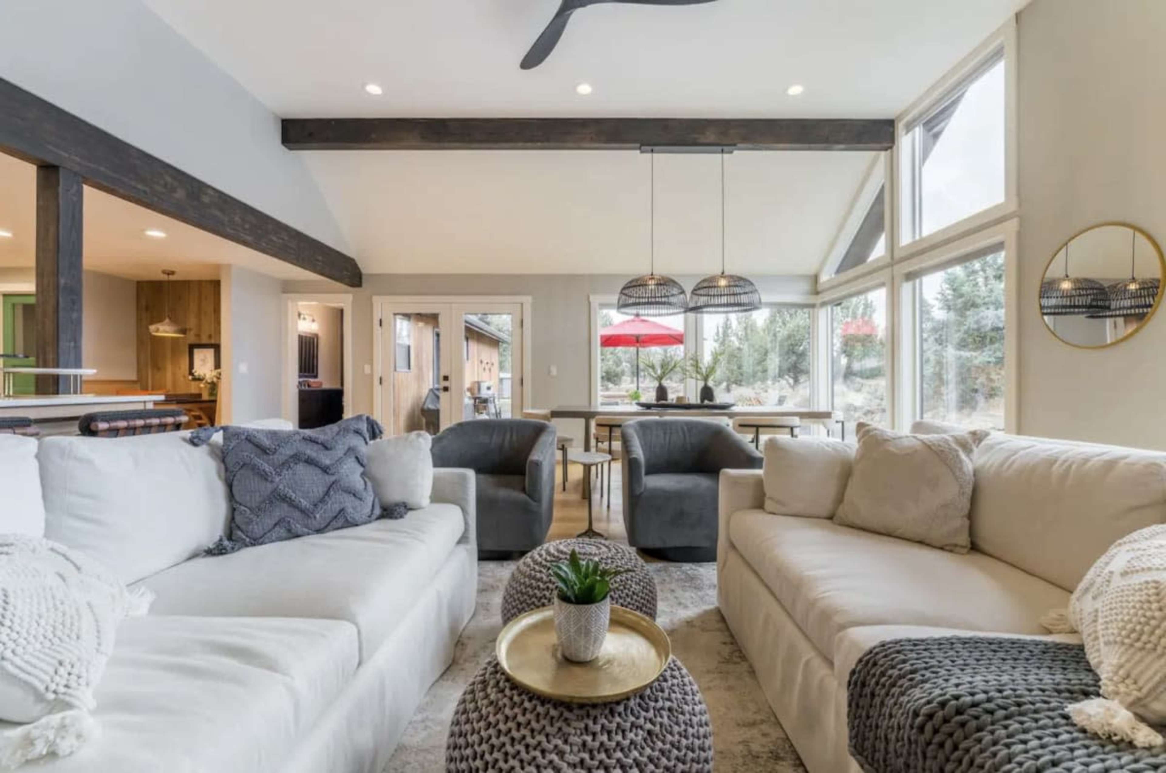A modern living room with two light-colored sofas, a round coffee table, and large windows providing natural light.