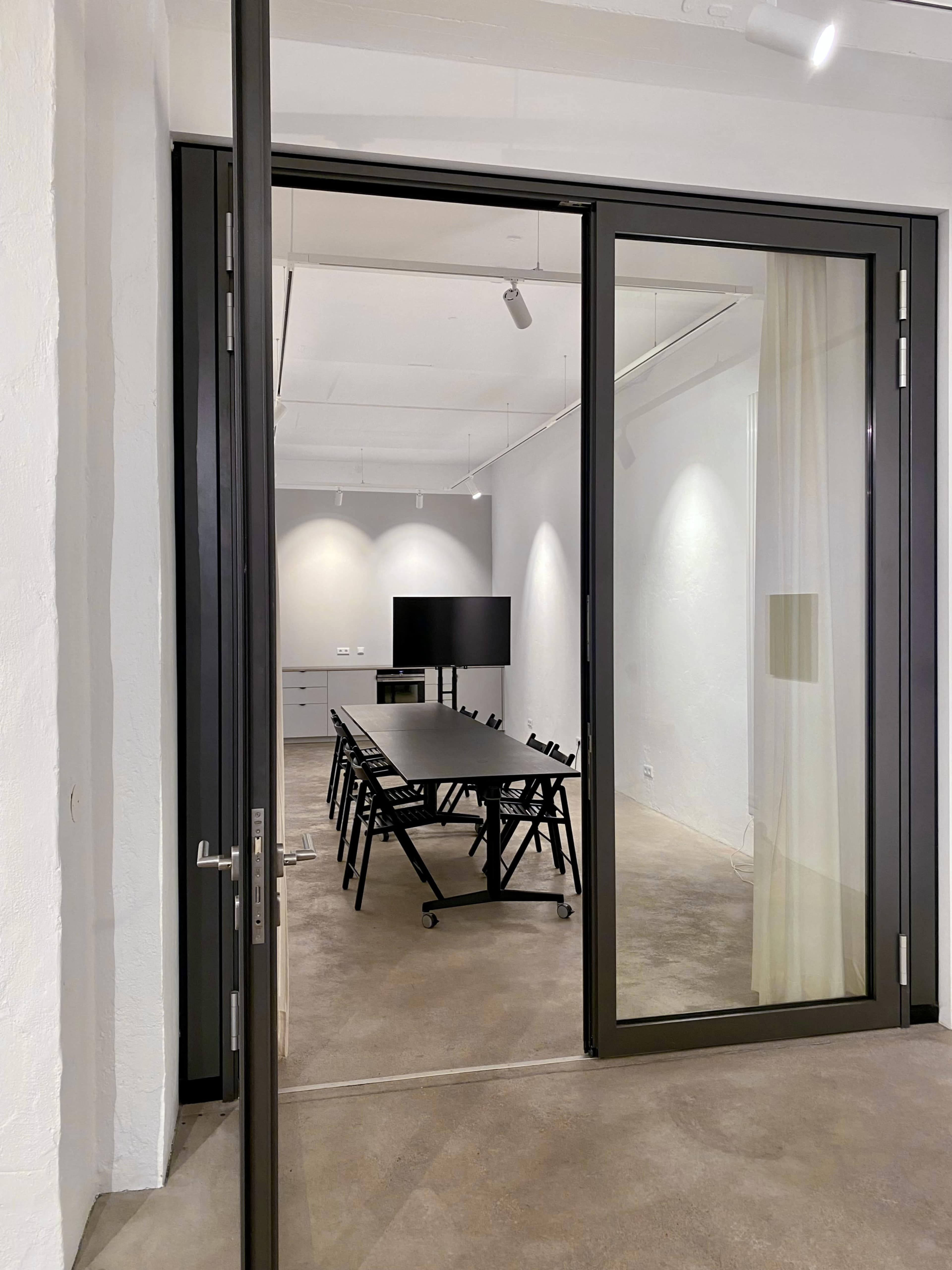 A conference room is visible through a glass door, featuring a long table and a television screen.