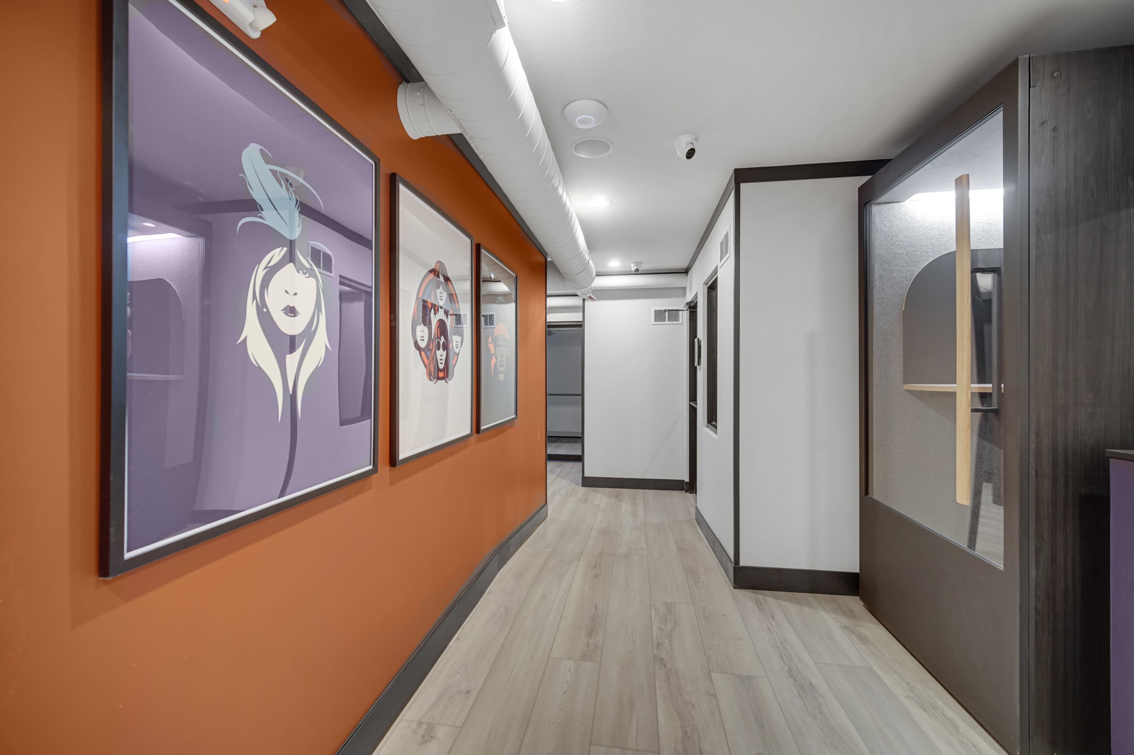 The image shows a modern hallway featuring colorful artwork on one wall and sleek, minimalist design elements.