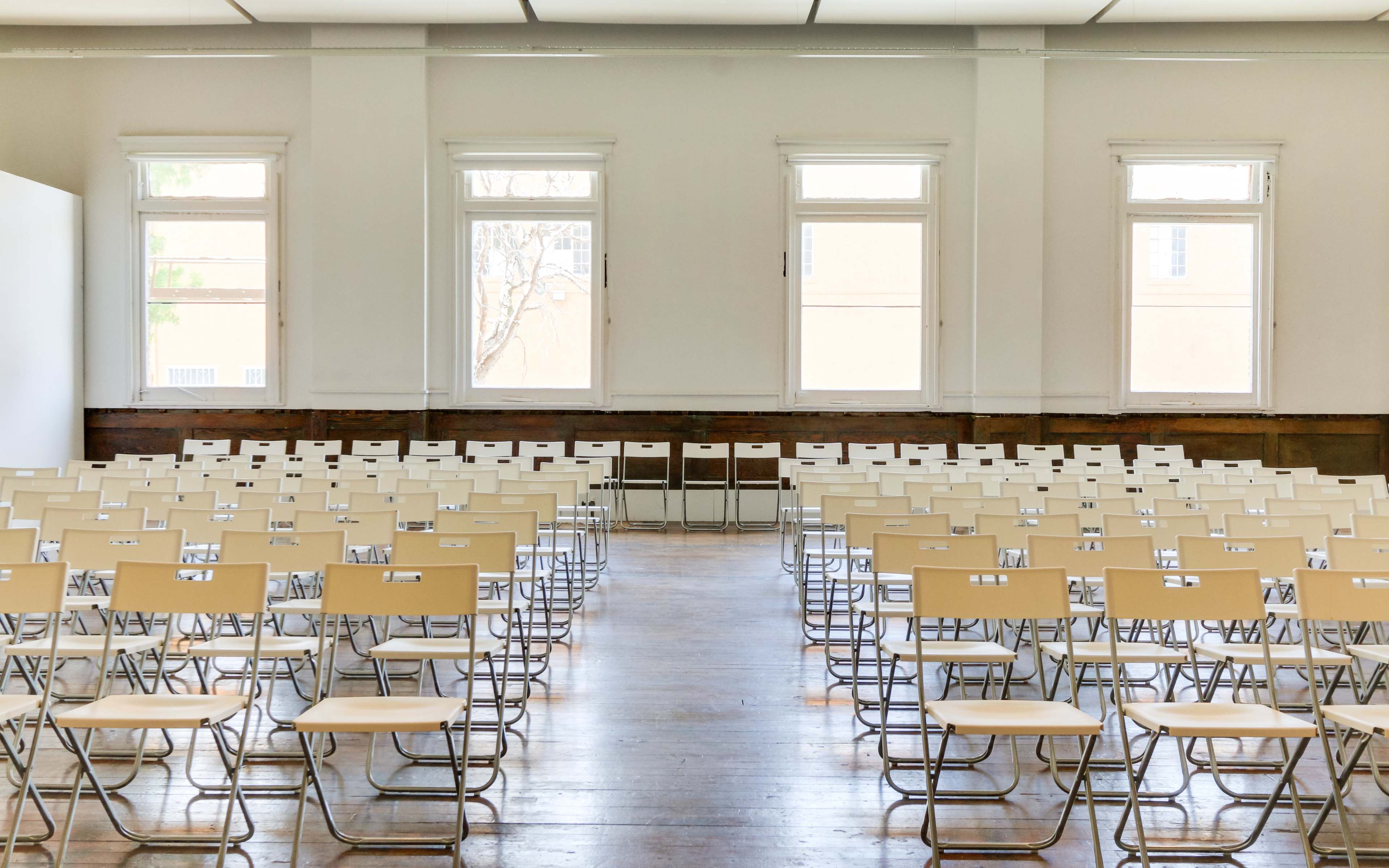 A spacious room with rows of empty folding chairs arranged in a grid pattern.