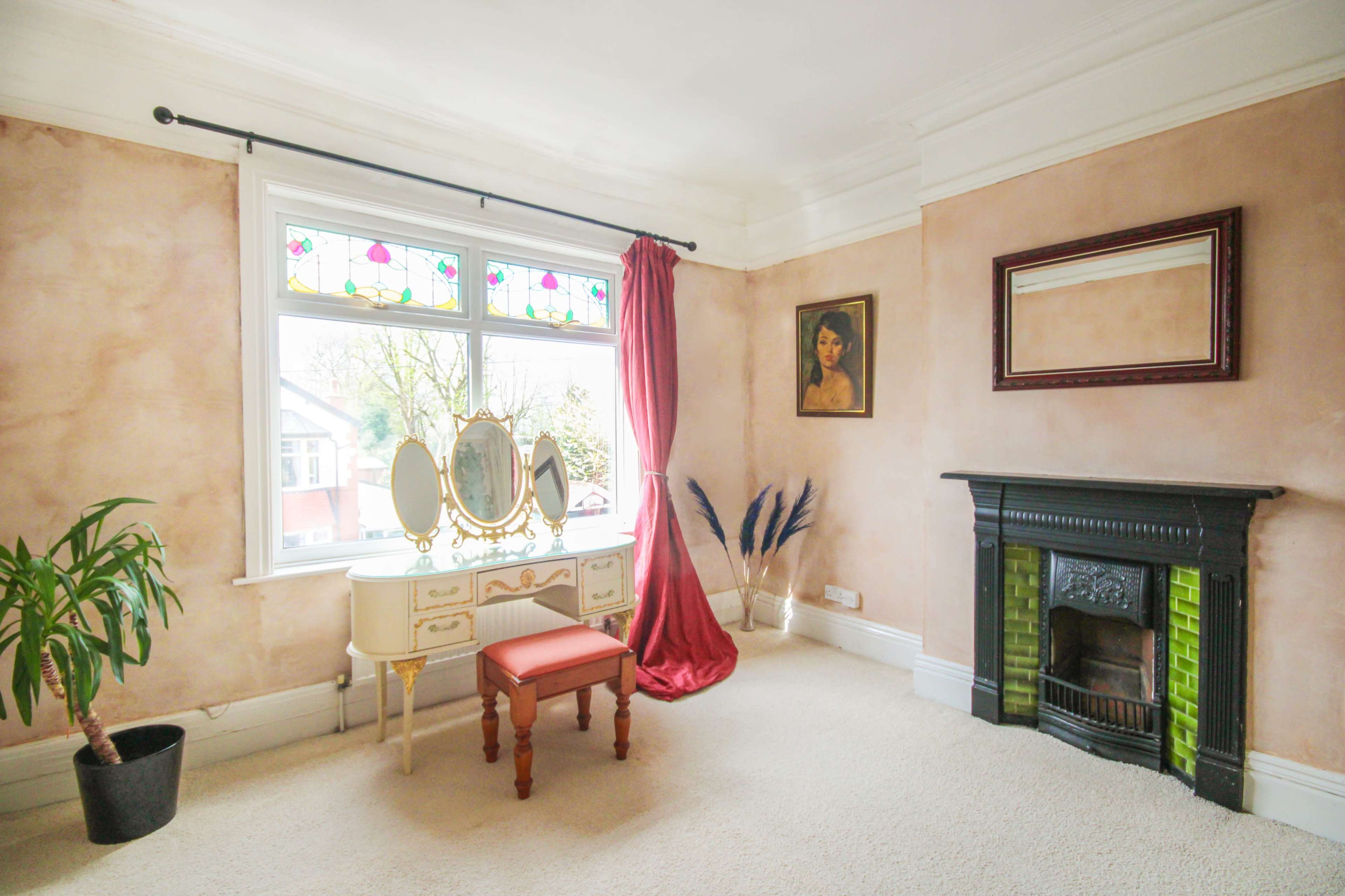The room features a vintage dressing table with a mirror, a red curtain by the window, and a decorative fireplace.