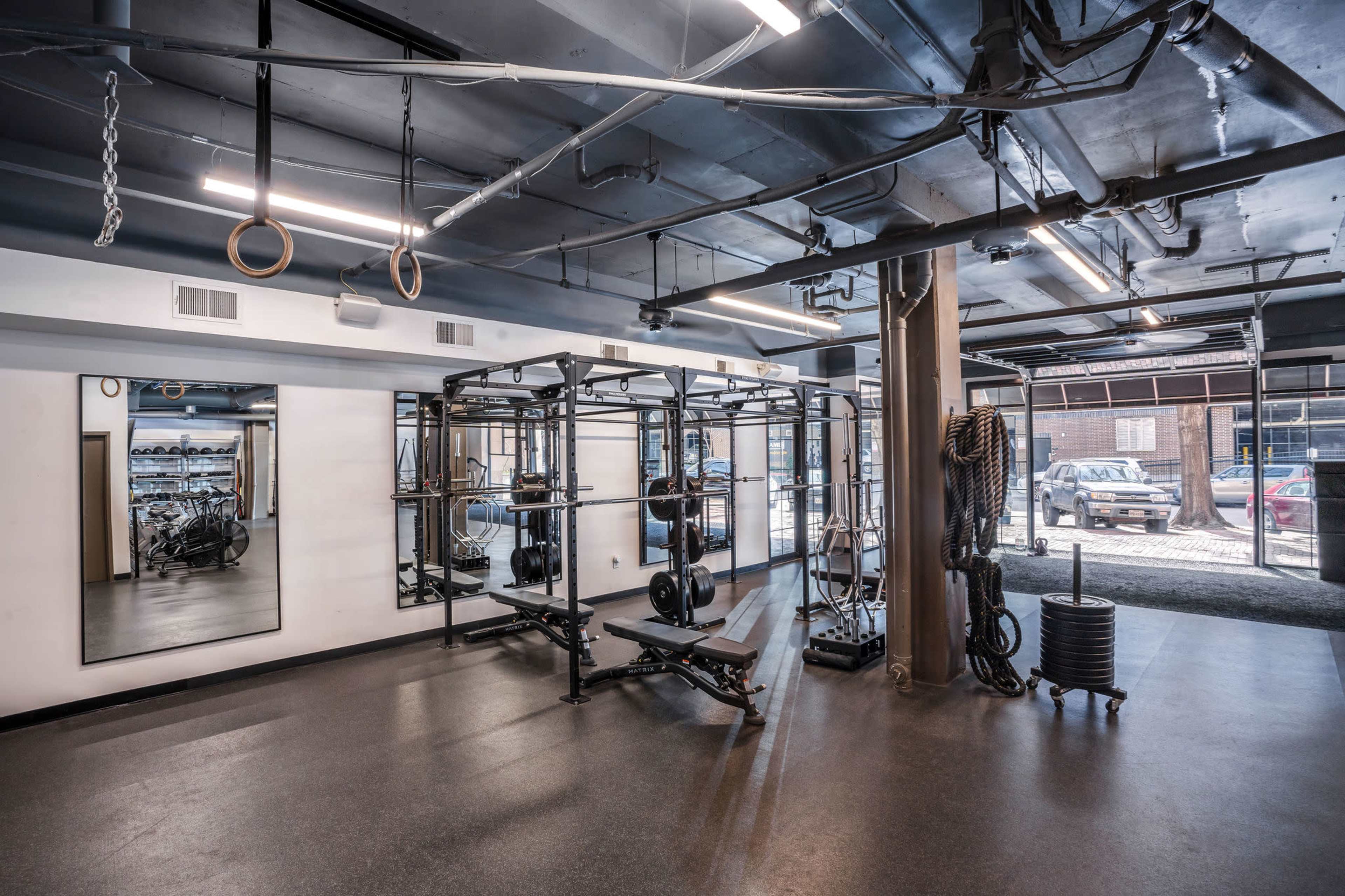 A spacious gym interior featuring exercise equipment, weightlifting stations, and mirrors.