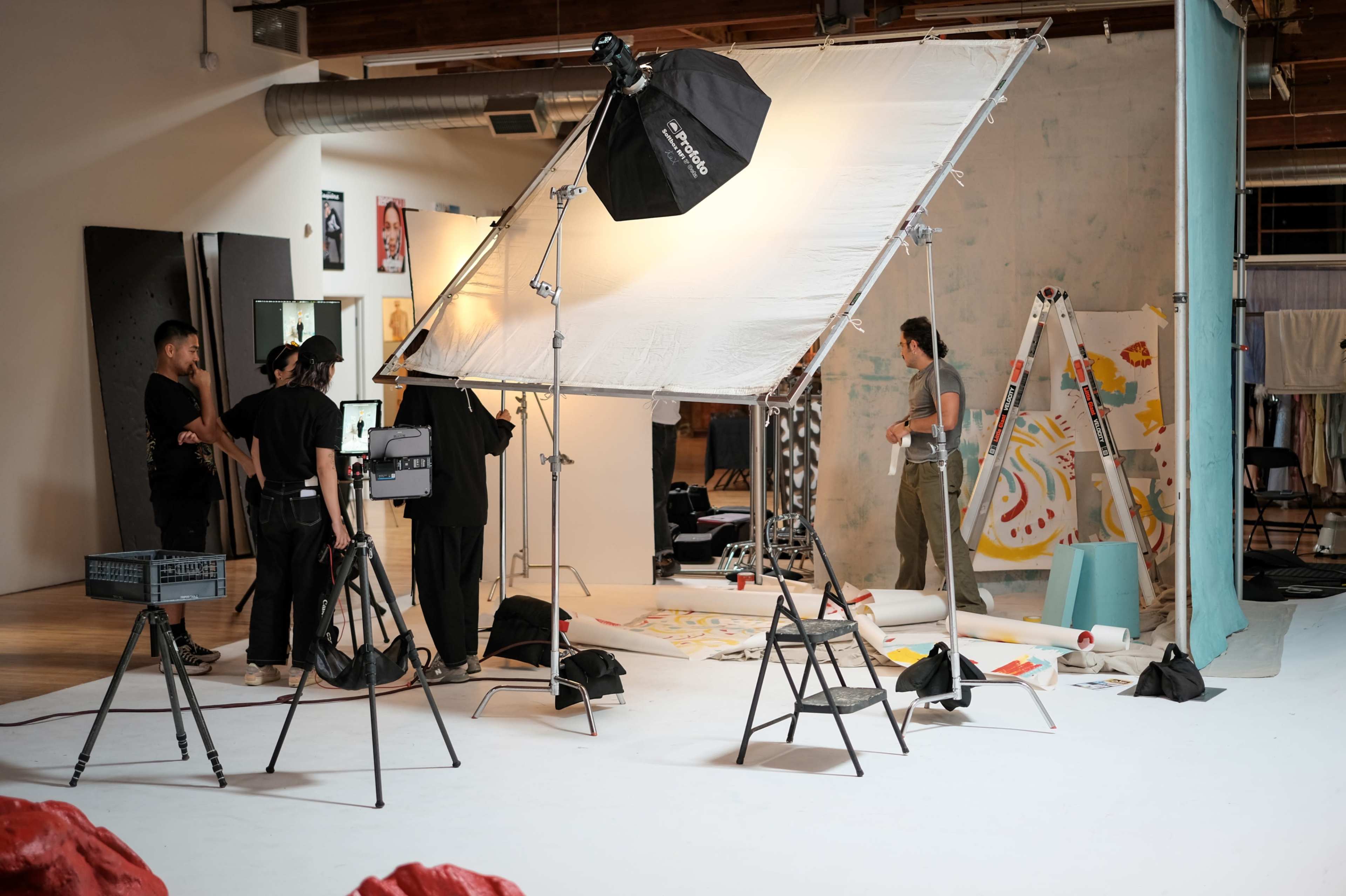 A photography studio is set up with lights, cameras, and a crew preparing for a photoshoot.