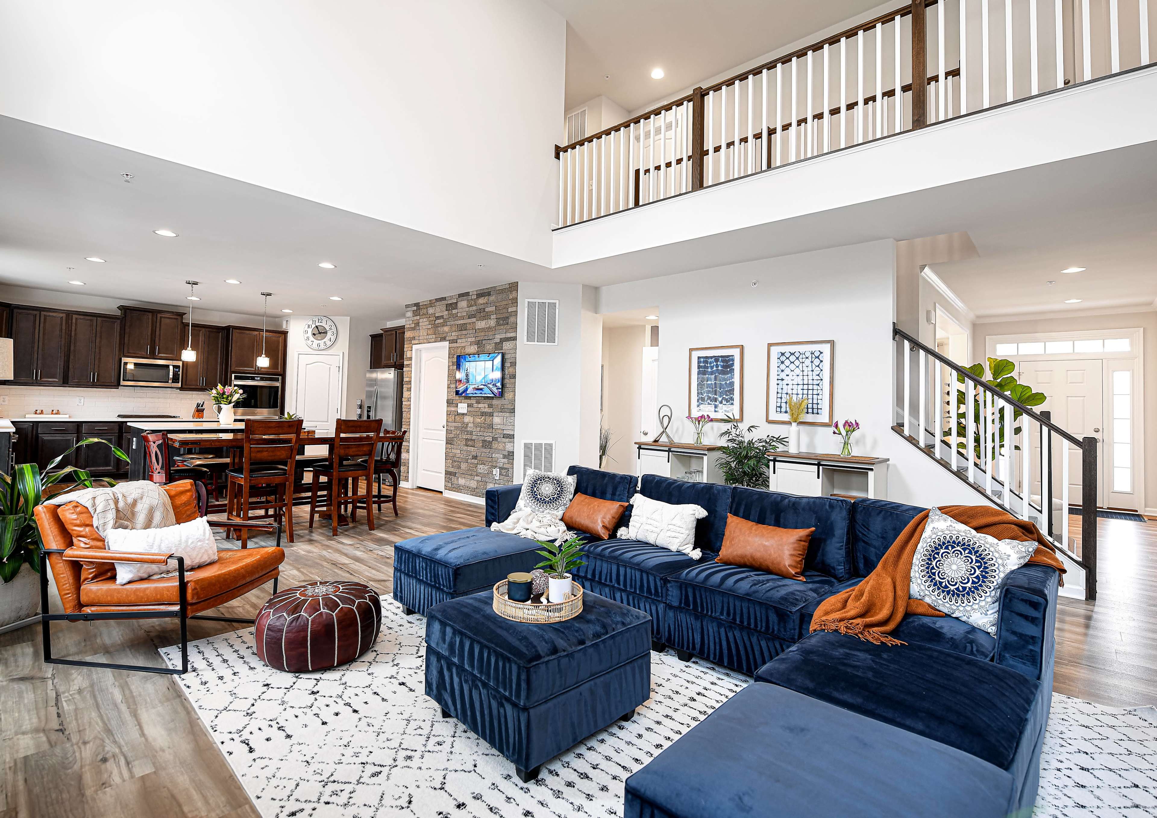 A modern living room with a navy blue sectional sofa, a coffee table, and a view of an open kitchen and dining area in the background.