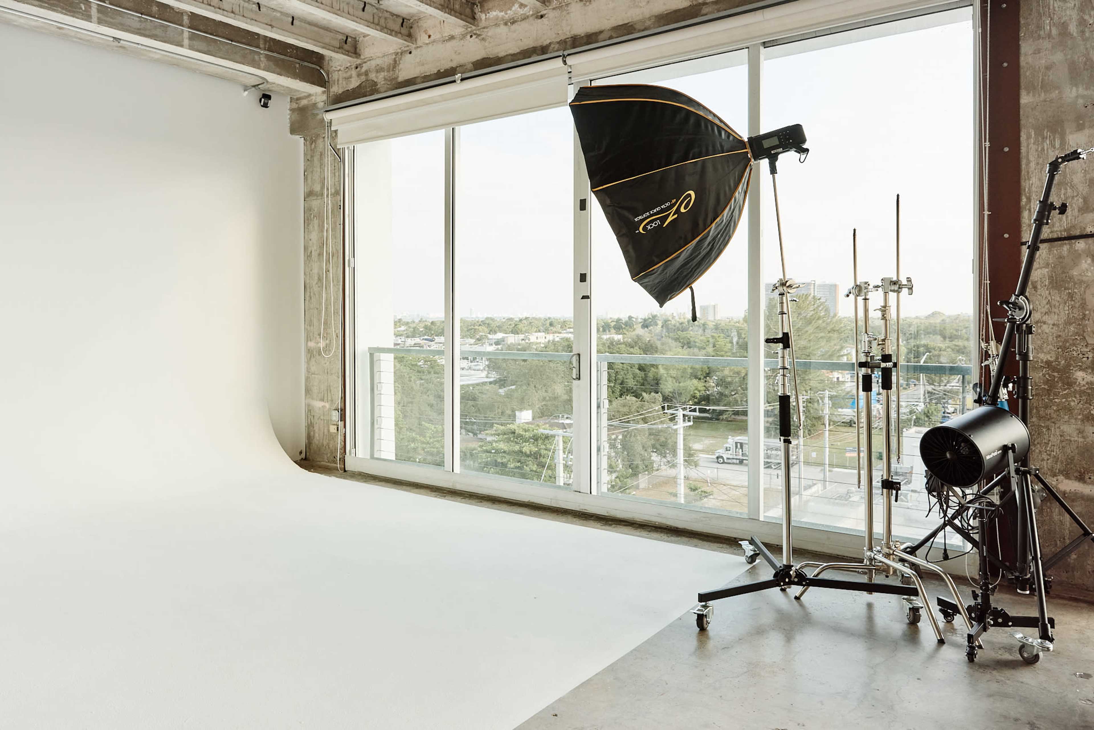 A photography studio with a large softbox light positioned near a window overlooking a cityscape.