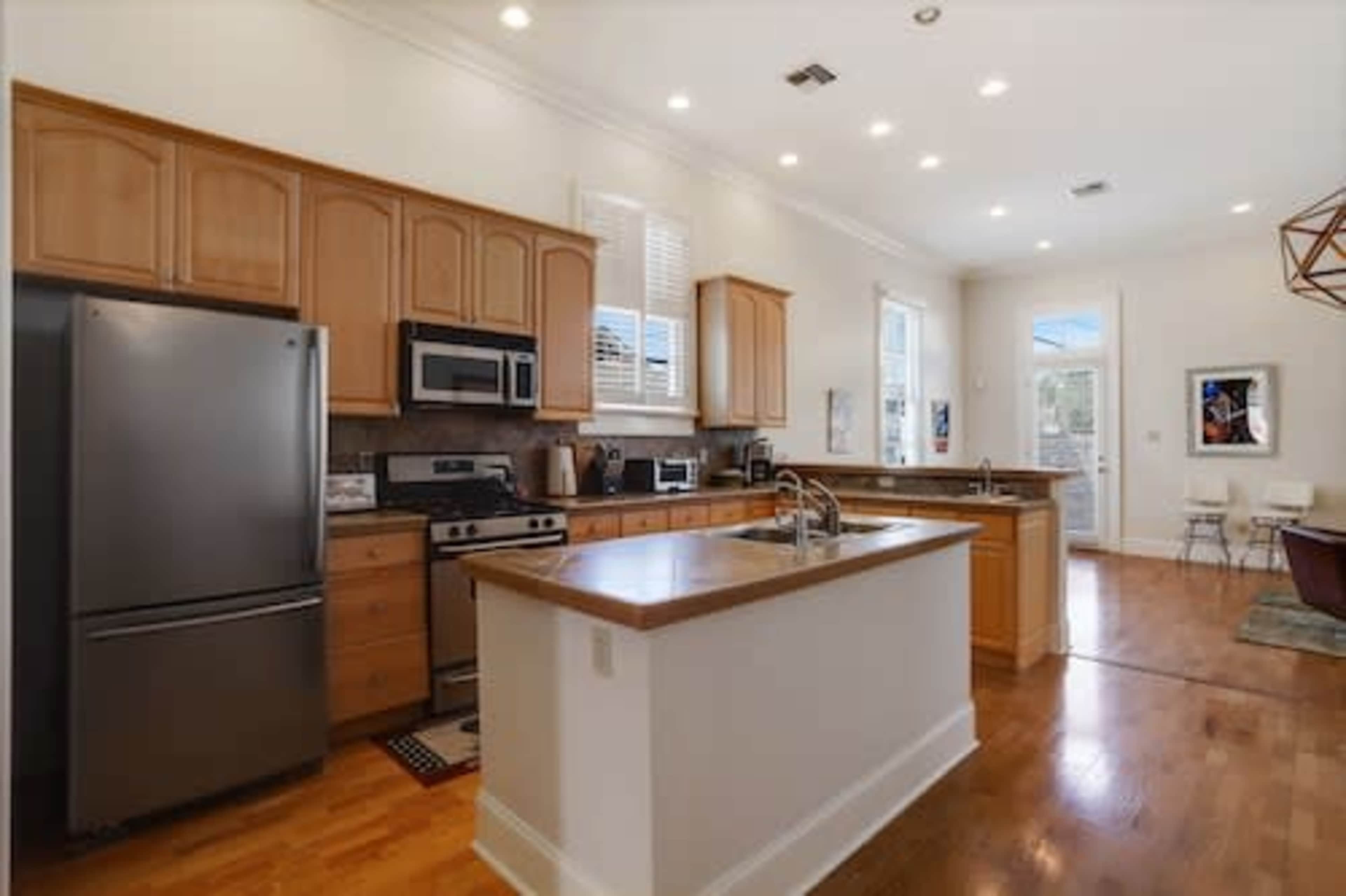 A modern kitchen with wooden cabinetry, stainless steel appliances, and an island with a wooden countertop.
