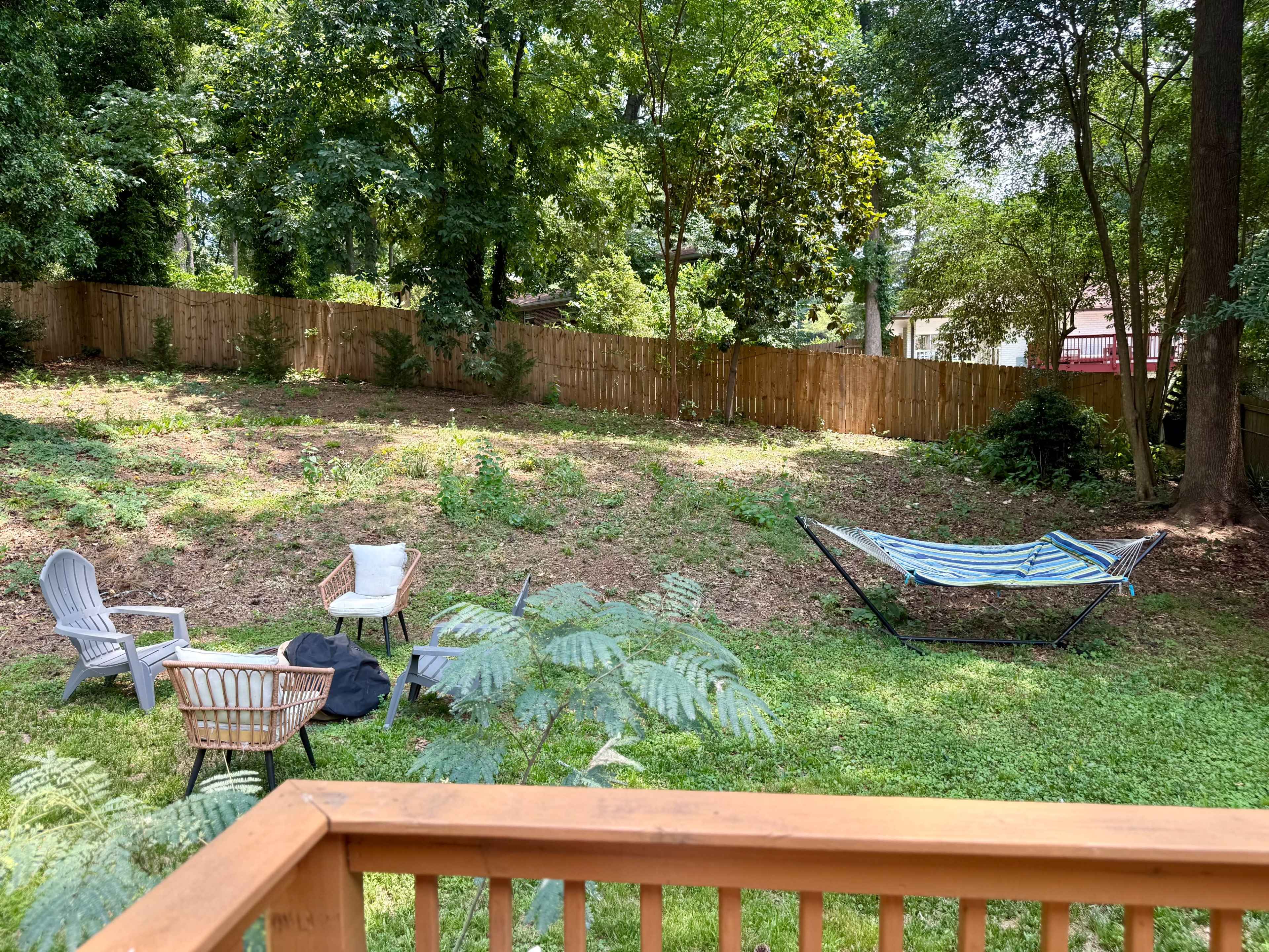 The image shows a grassy backyard with a few scattered chairs, a hammock, and a wooden fence in the background.