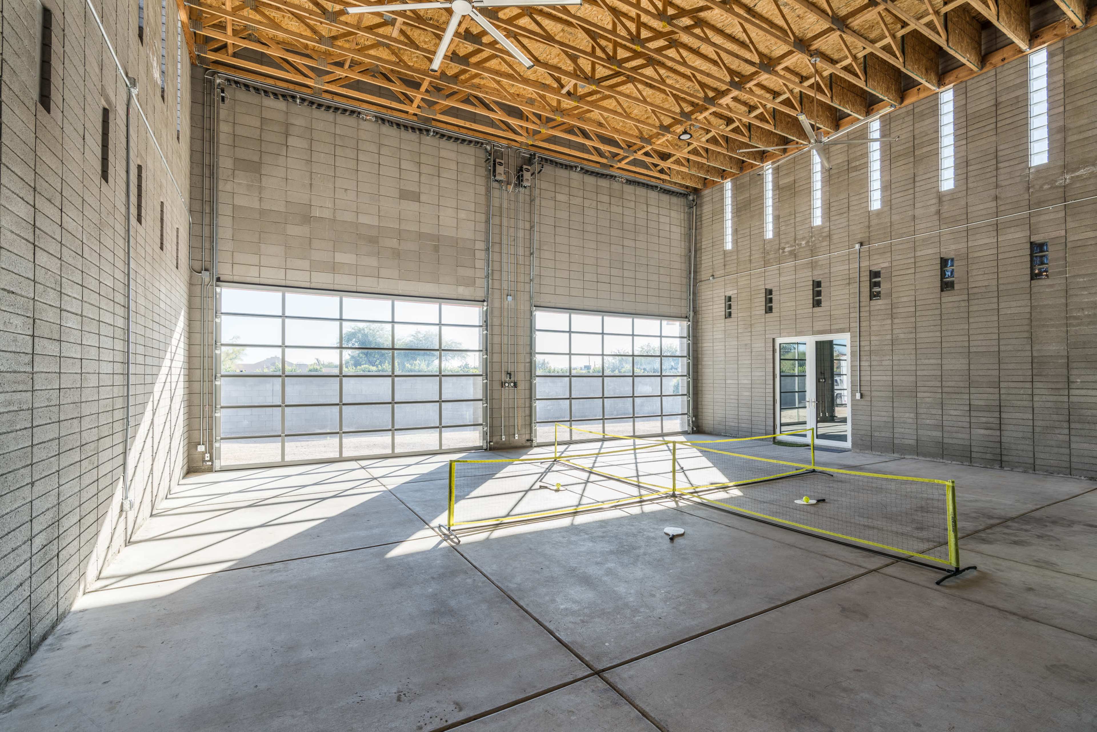 An empty industrial space with high ceilings, large windows, and unfinished concrete walls.