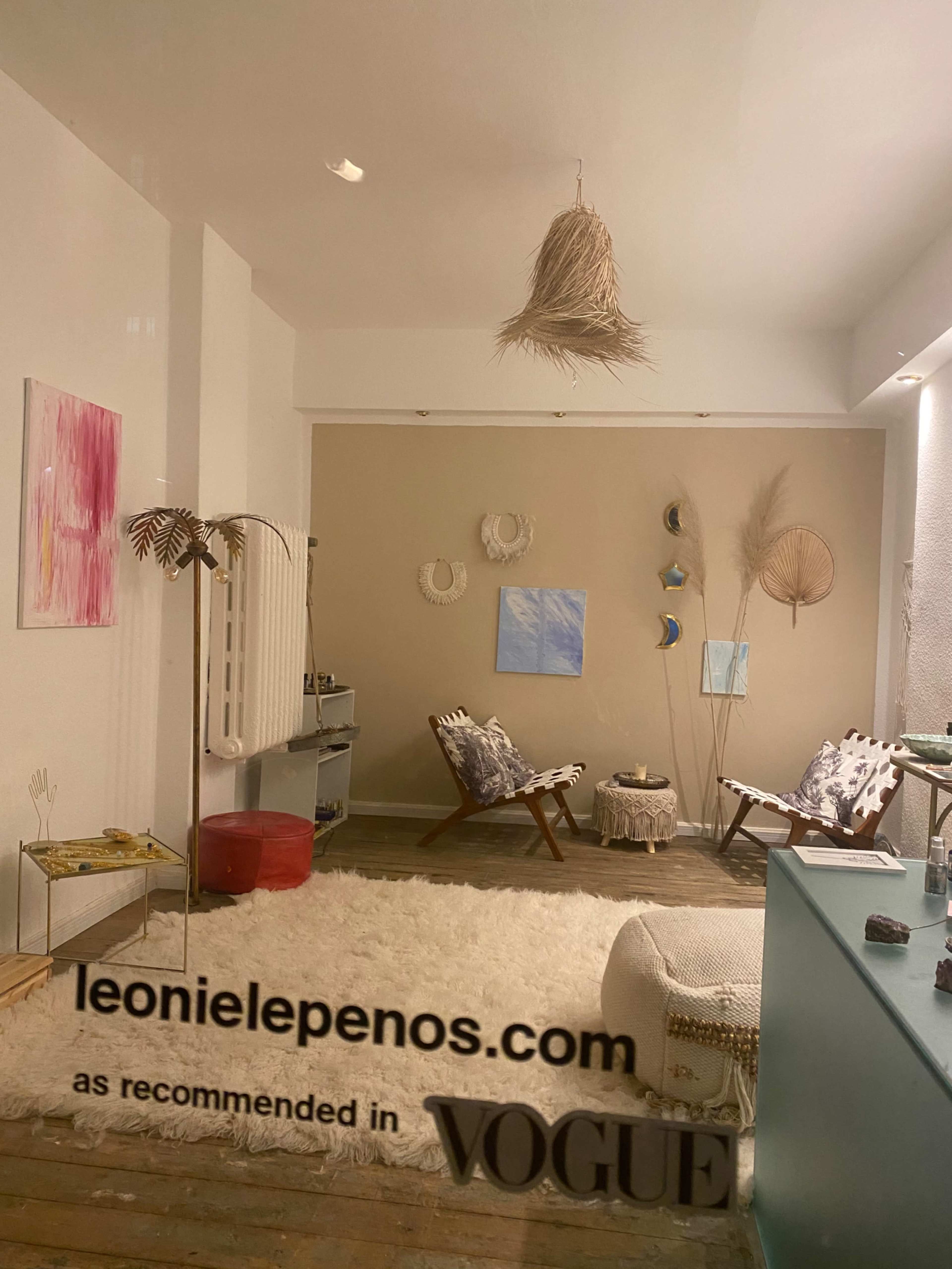 The image shows a modern, minimalist interior featuring a large white rug, a light-colored wall with decorative wall hangings, and contemporary furniture arranged in a cozy setting.