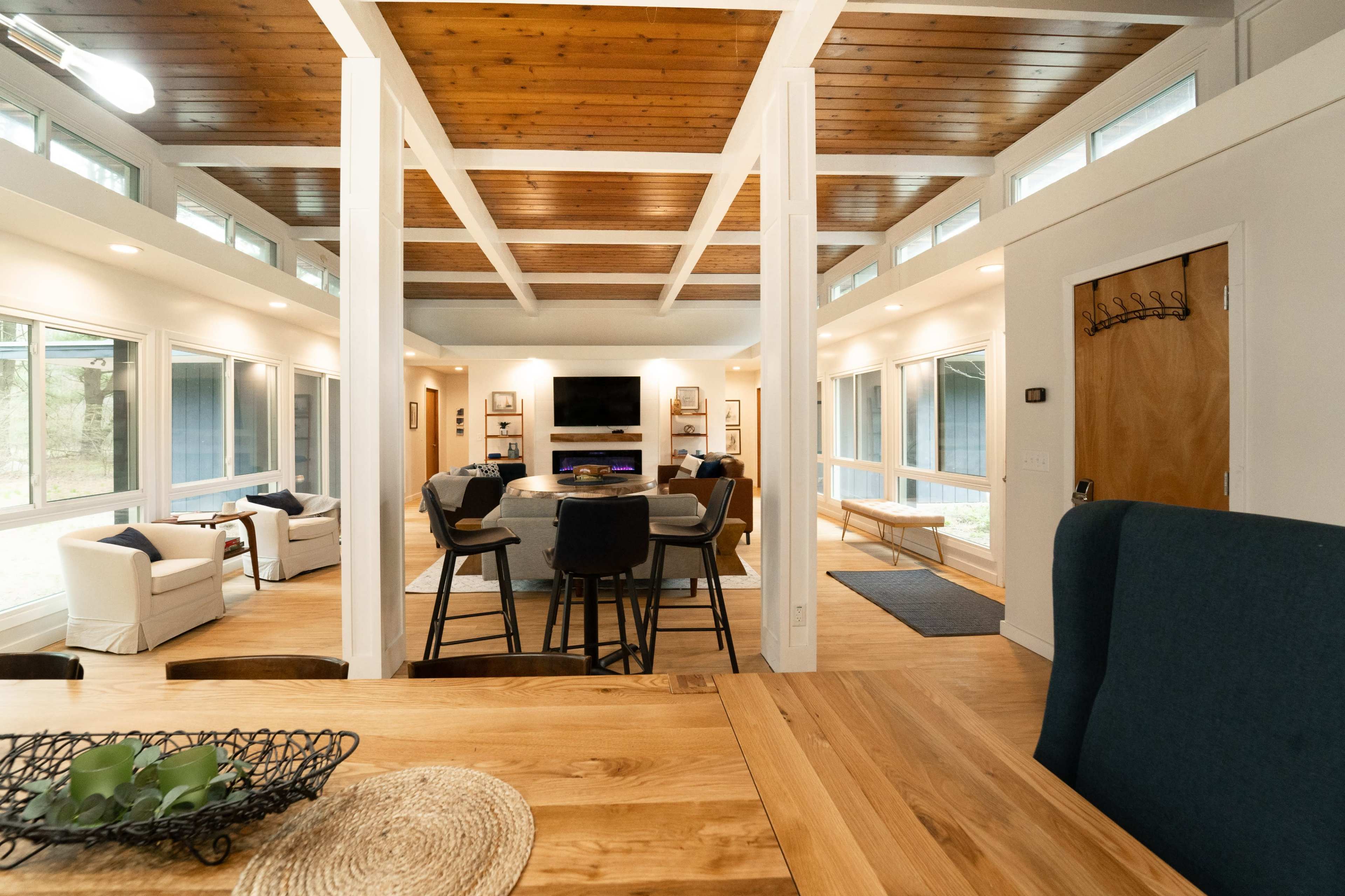 A spacious, open-concept living area with a dining table, seating arrangements, and large windows allowing natural light to enter.