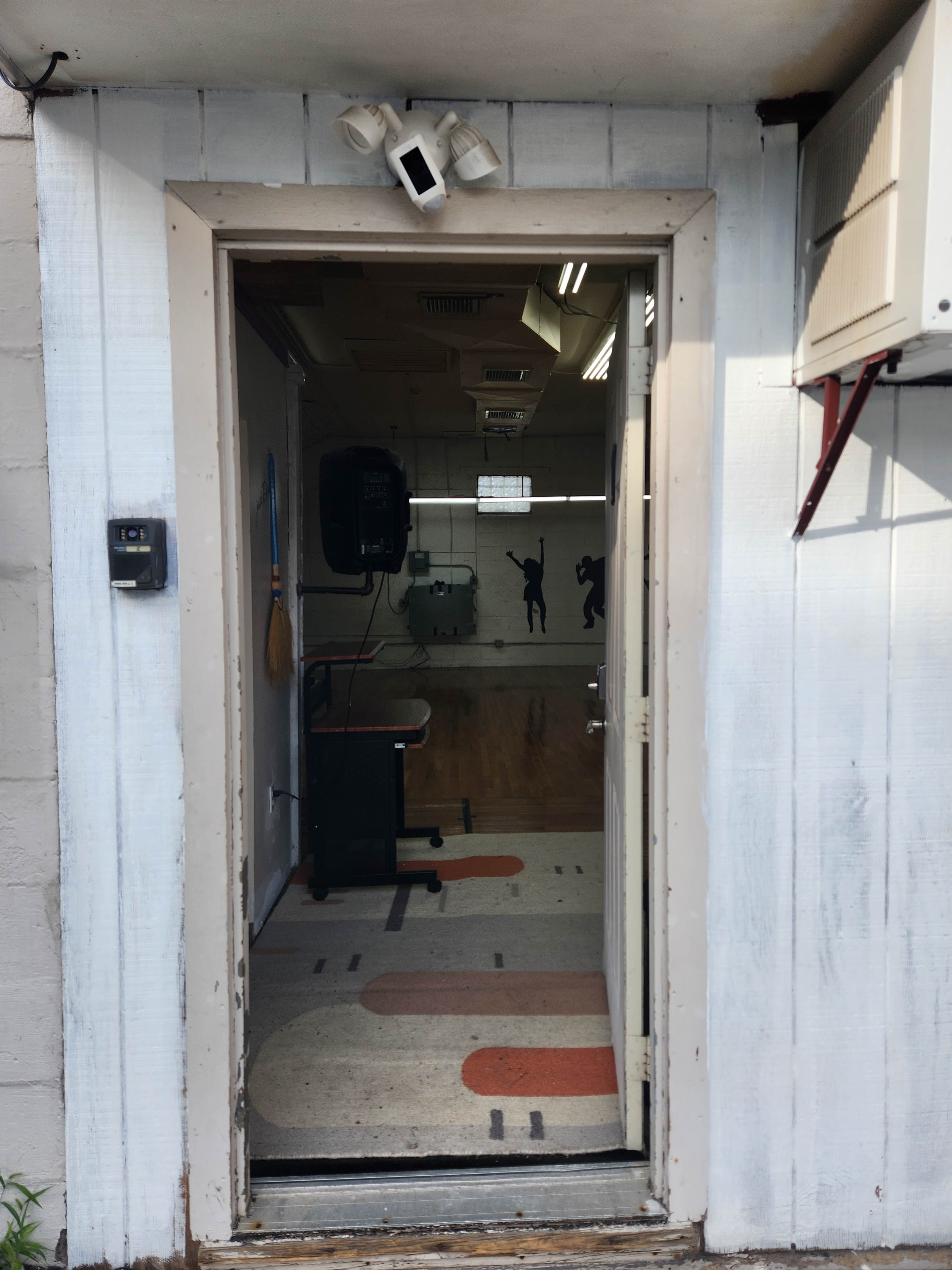 An open door leading into a room with a patterned floor and visible equipment on the walls.