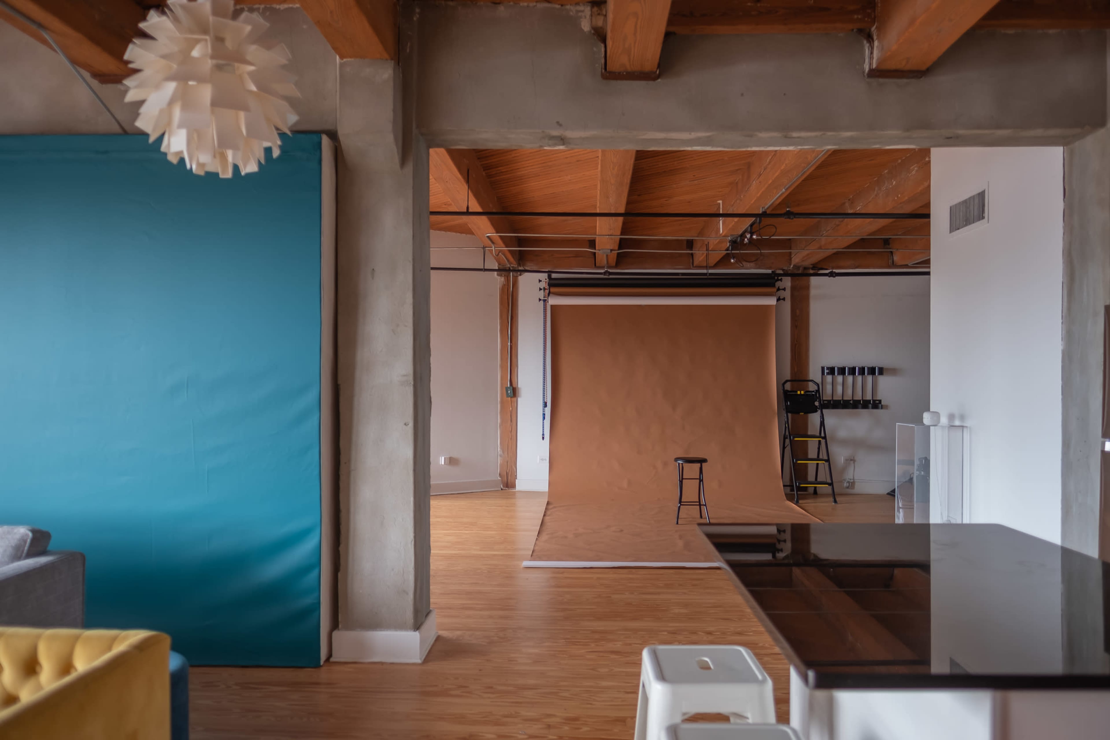 An interior space featuring a blue wall, a brown backdrop, a stool, and wooden beams across the ceiling.