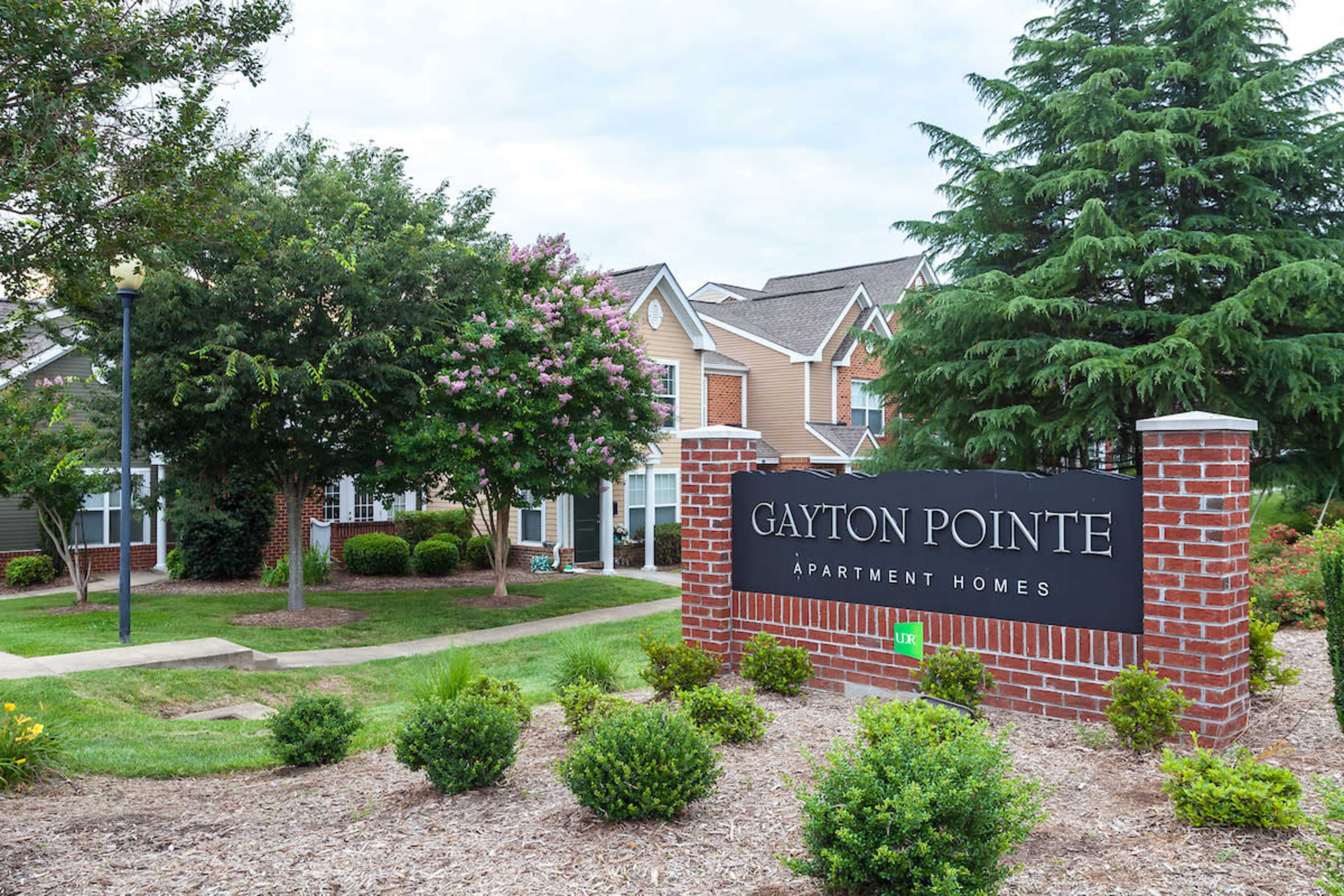 The entrance sign for Gayton Pointe Apartment Homes, surrounded by landscaped greenery and residential buildings in the background.