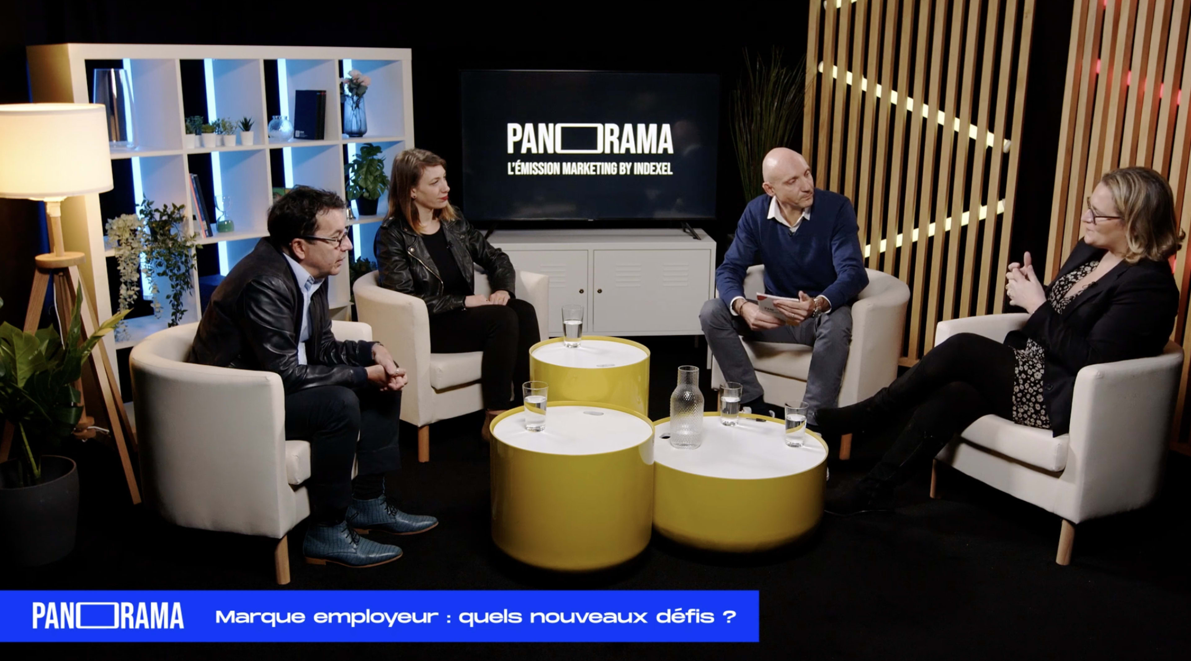A panel discussion takes place with four participants seated around a small table, focusing on employer branding challenges.