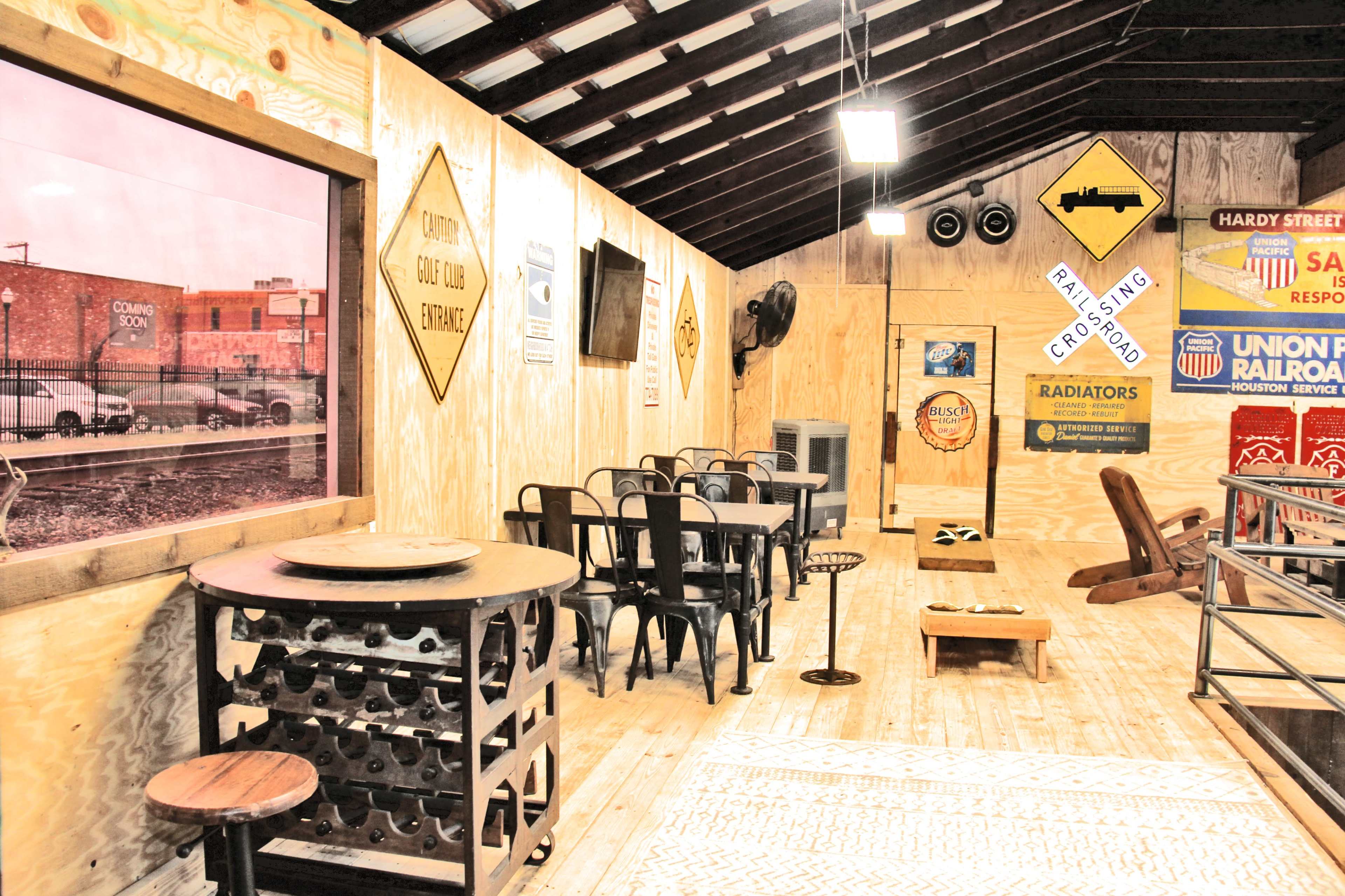 The interior of a wooden building features a dining area with metal chairs, a table, a vintage decoration setup, and wooden flooring.