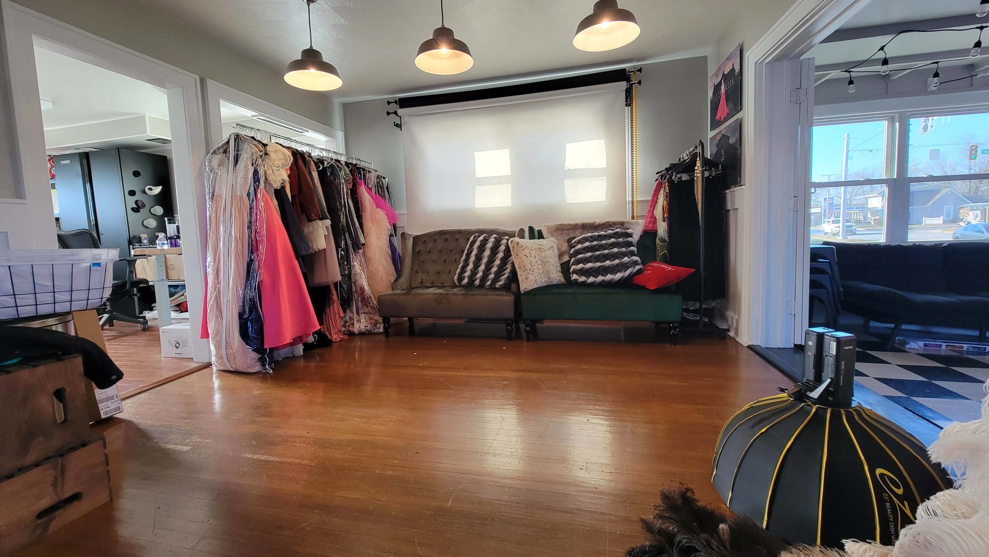 A spacious room with a couch facing a backdrop, surrounded by clothing racks filled with various garments.