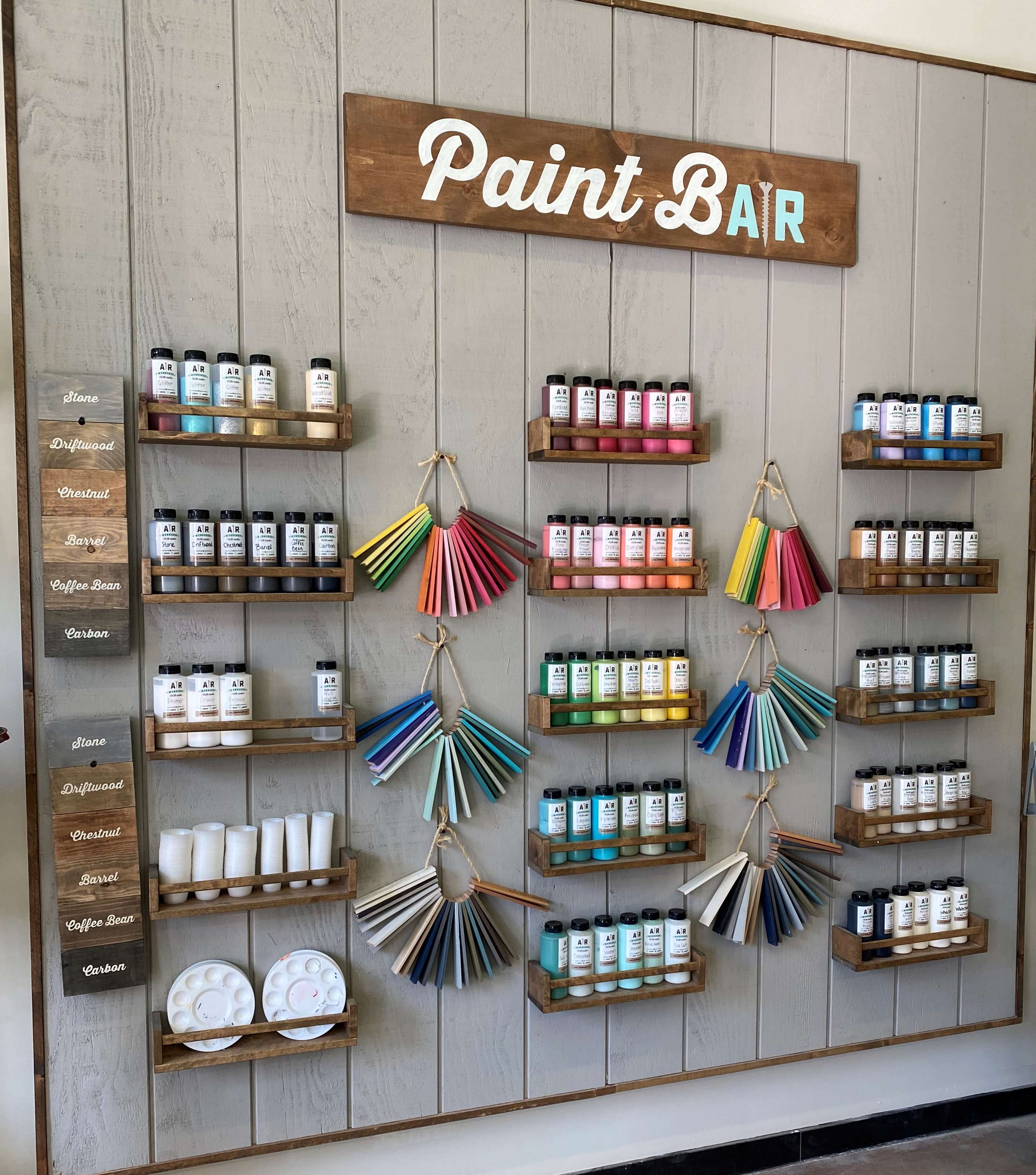 A wall display featuring organized paint bottles and color swatches at a paint bar.