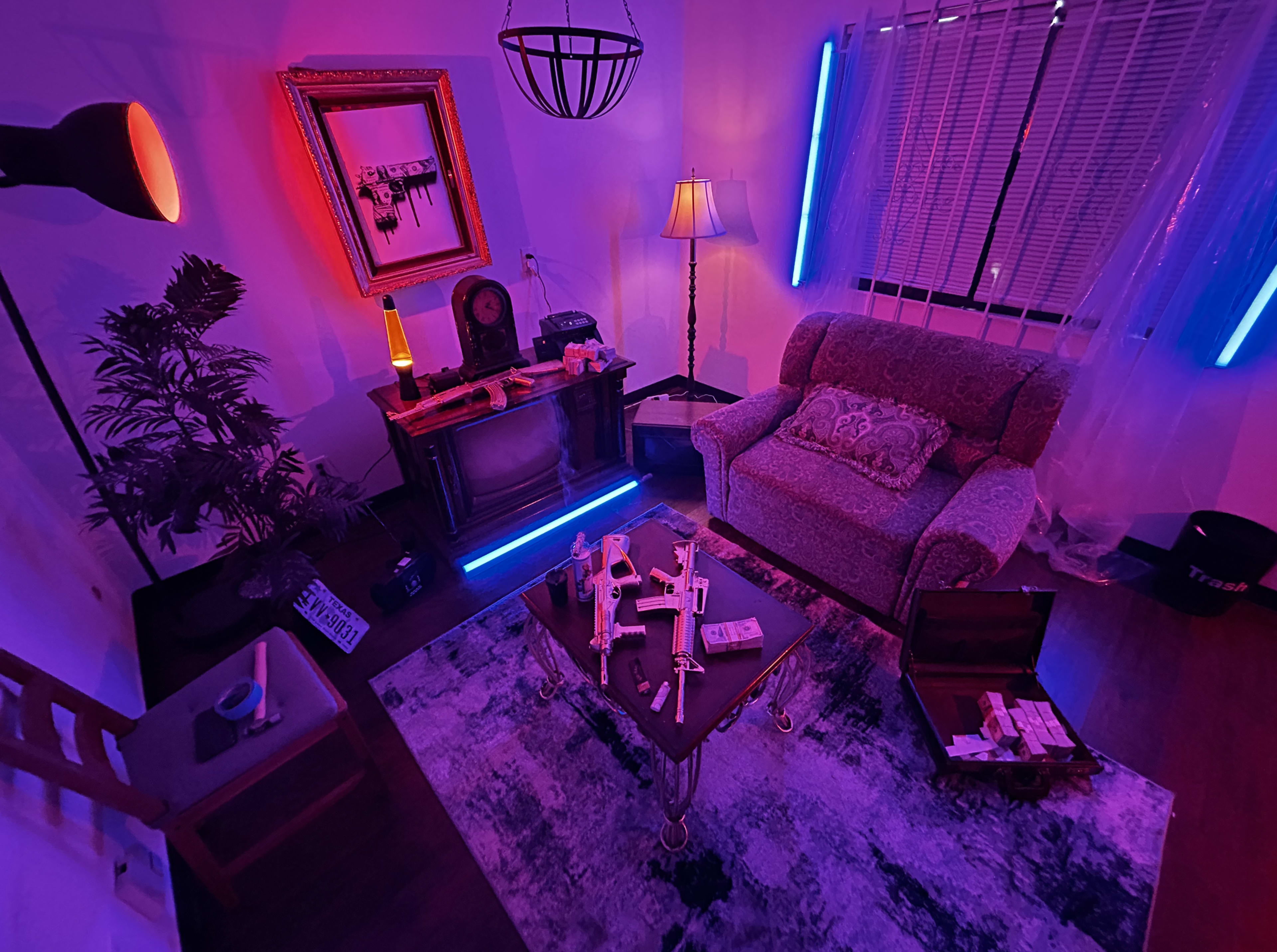 A cozy room features a couch, decorative lamp, and a table adorned with various small items, all illuminated by purple and blue lighting.